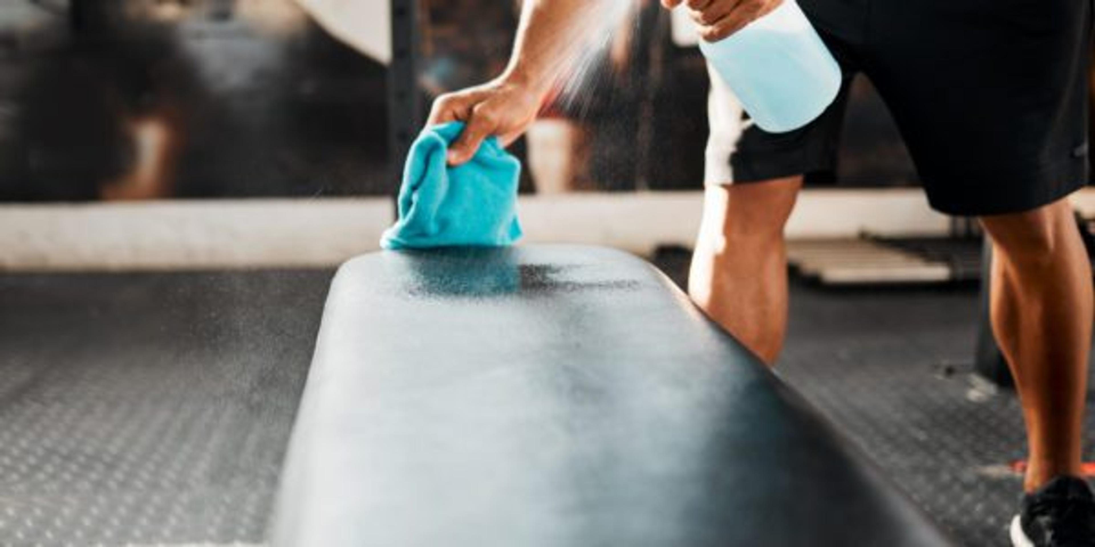 Man disinfecting workout equipment at the gym.