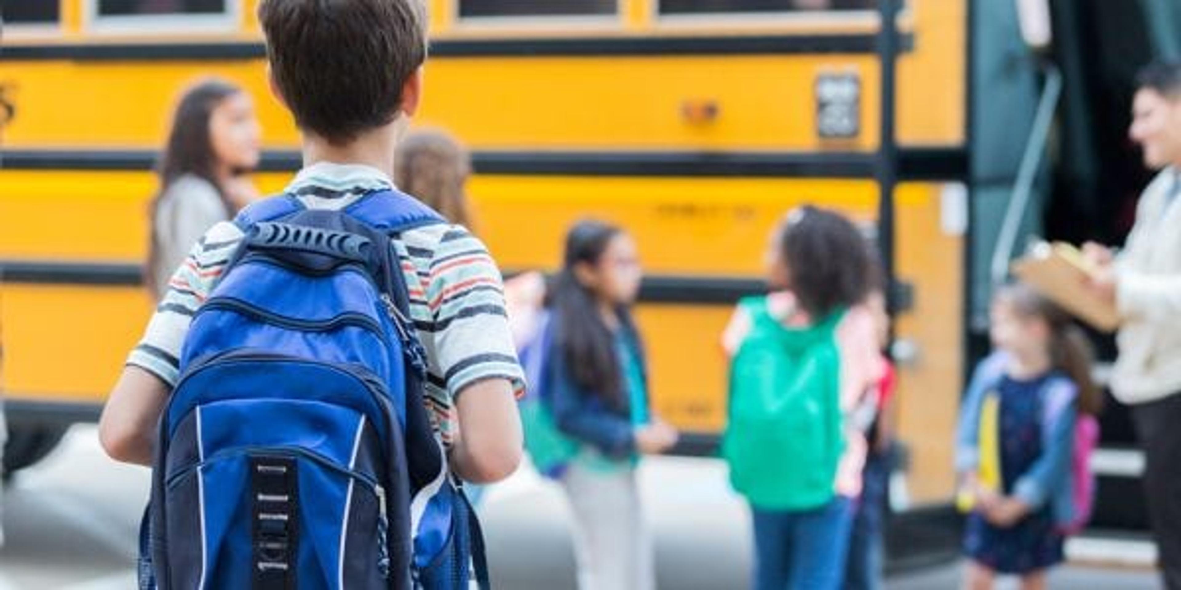 Young boy waits to load school bus