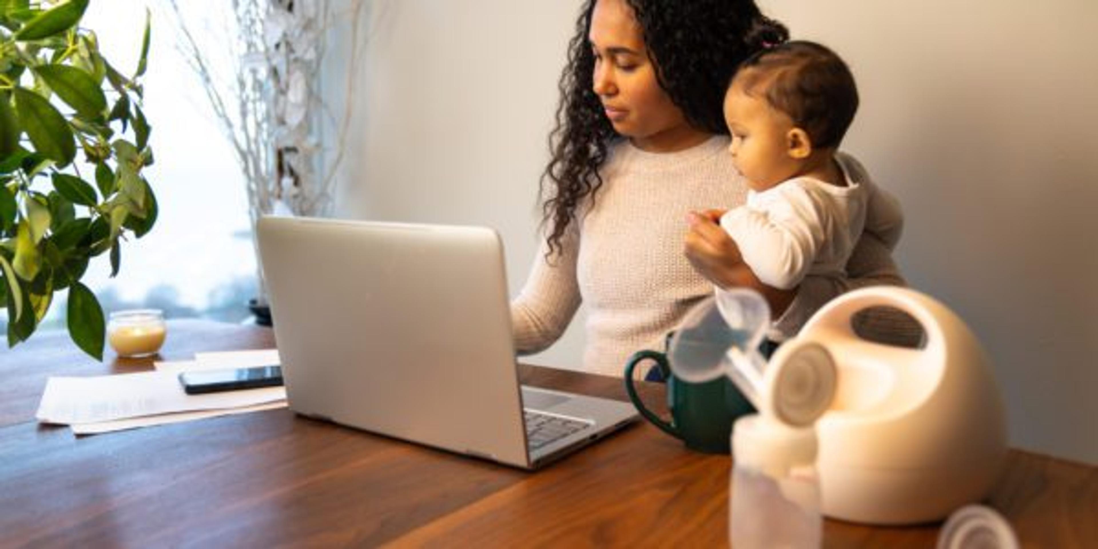 Young woman and her baby- sitting at the table with a breast pump