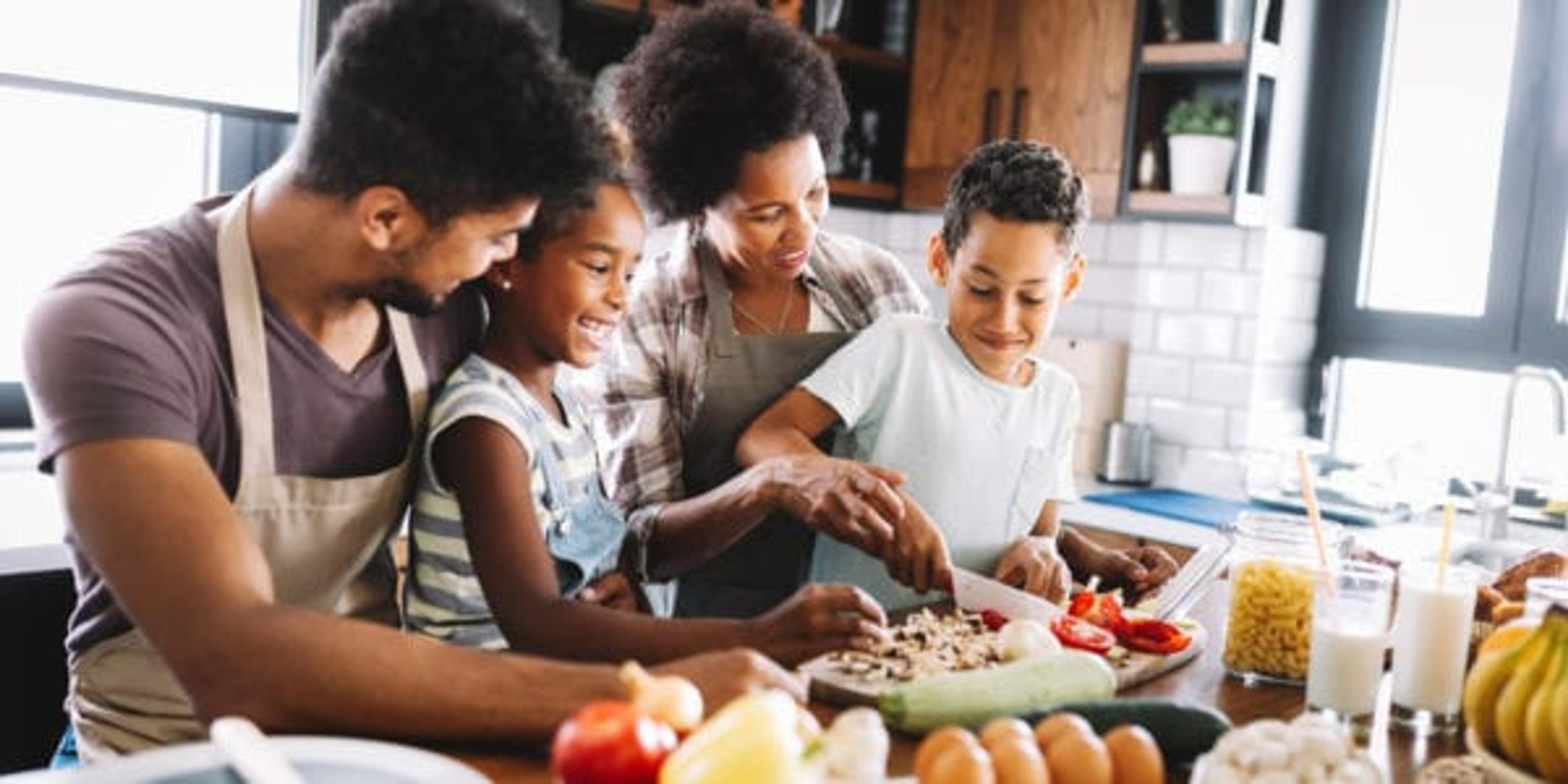 Happy african american family preparing healthy organic food together in kitchen