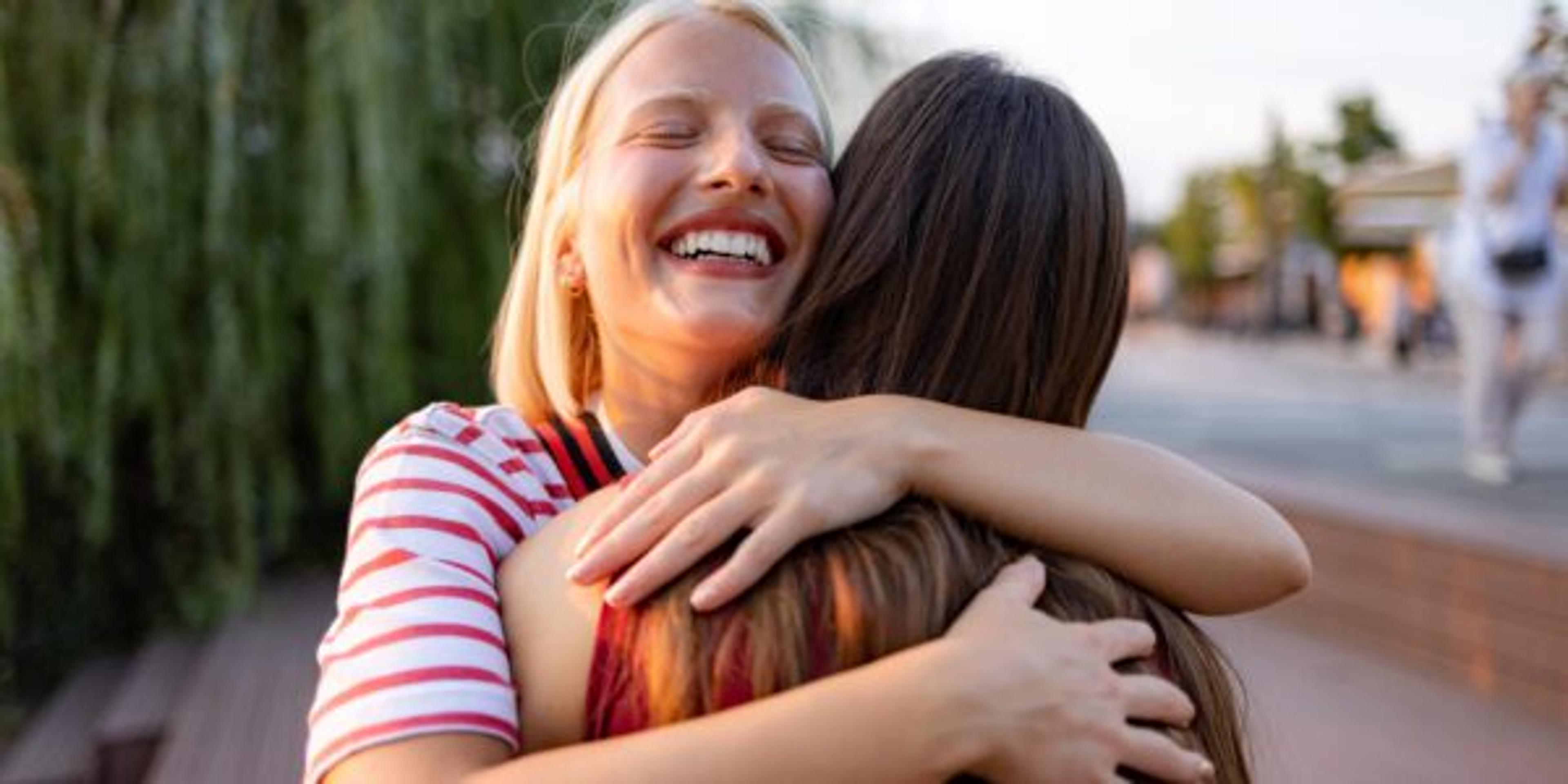 Happy woman embracing her friend on the street.