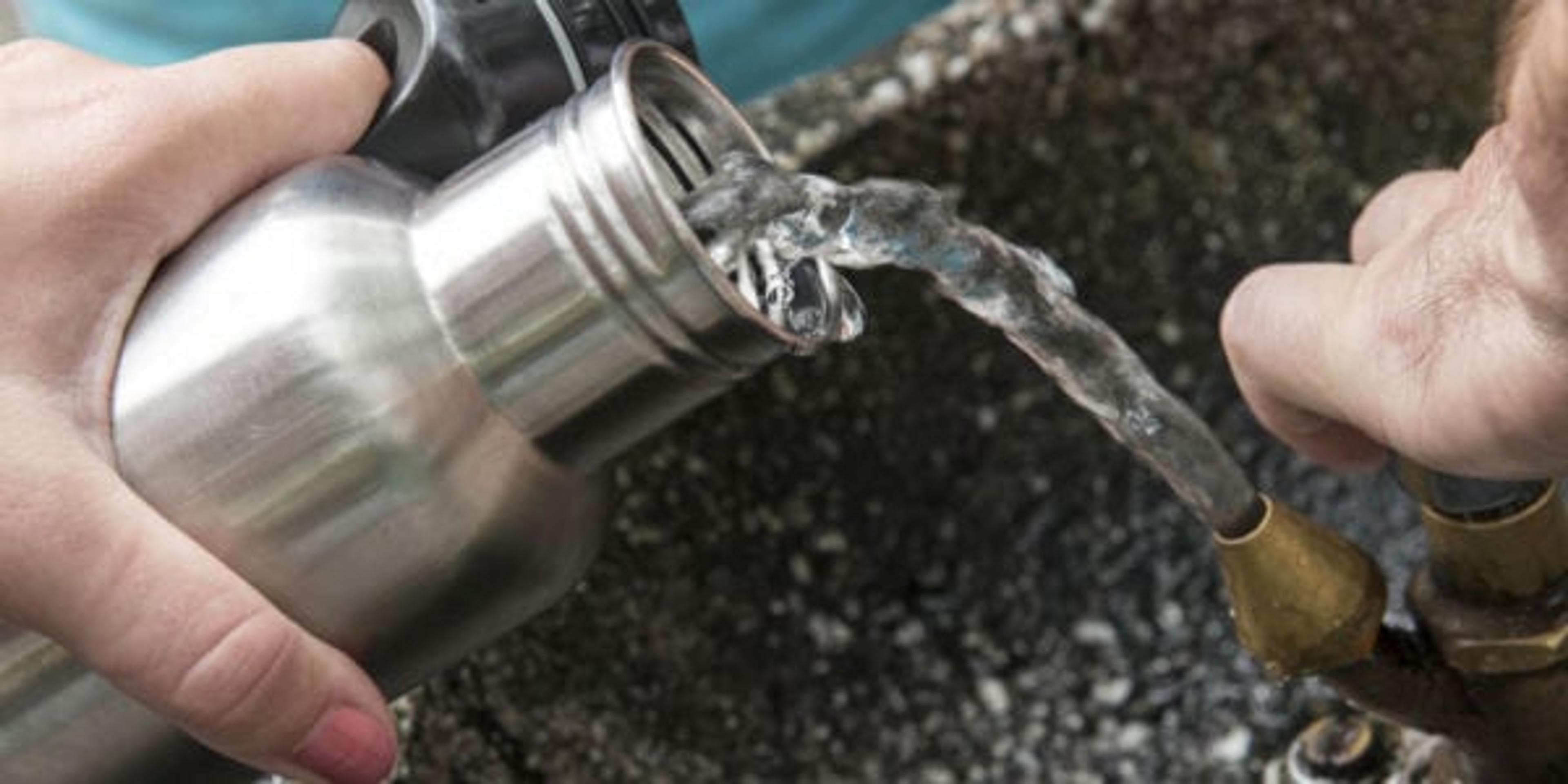 Image of hands filling a reusable water bottle from a water fountain.