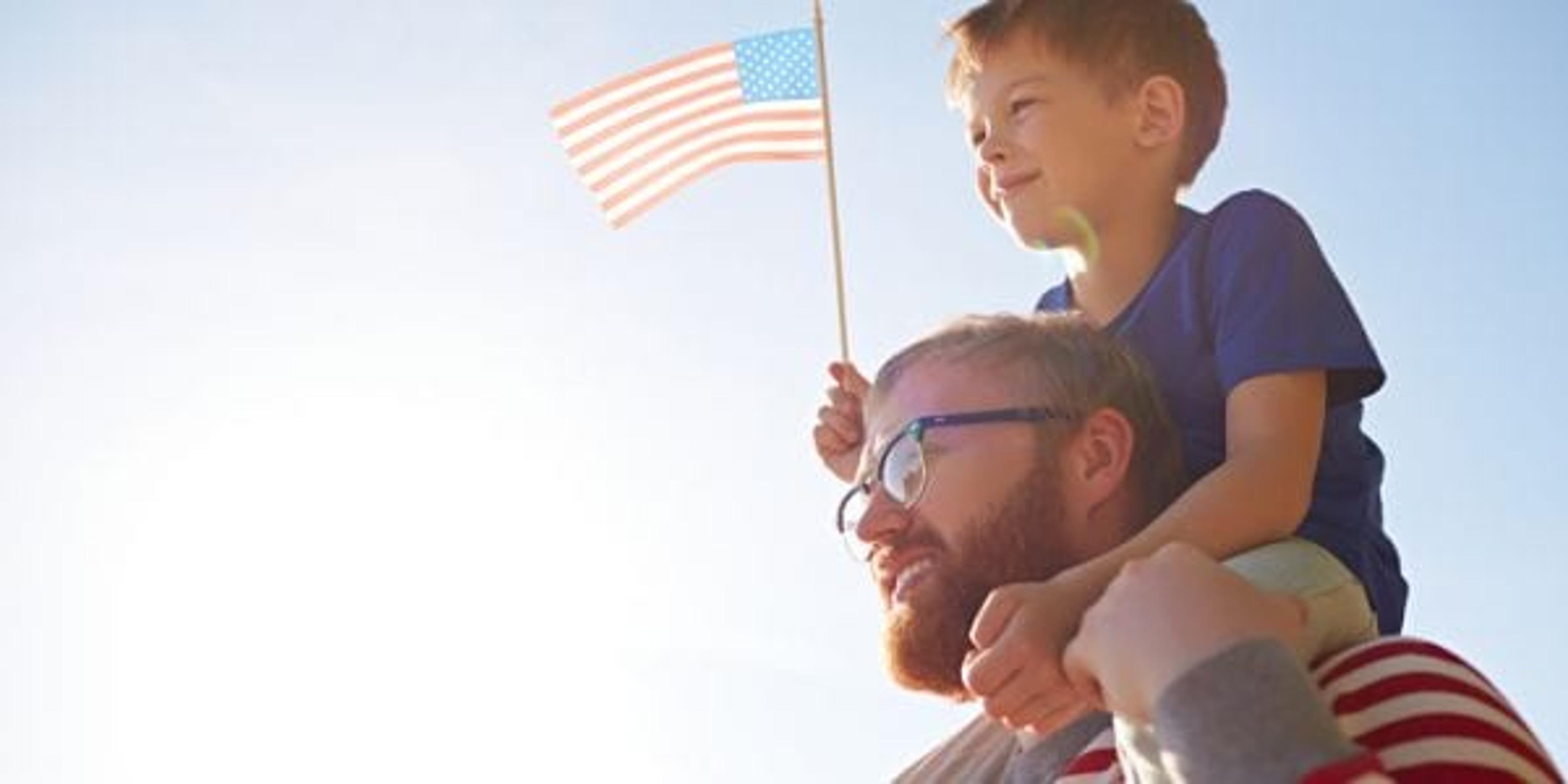 Father and son at parade holding an American flag
