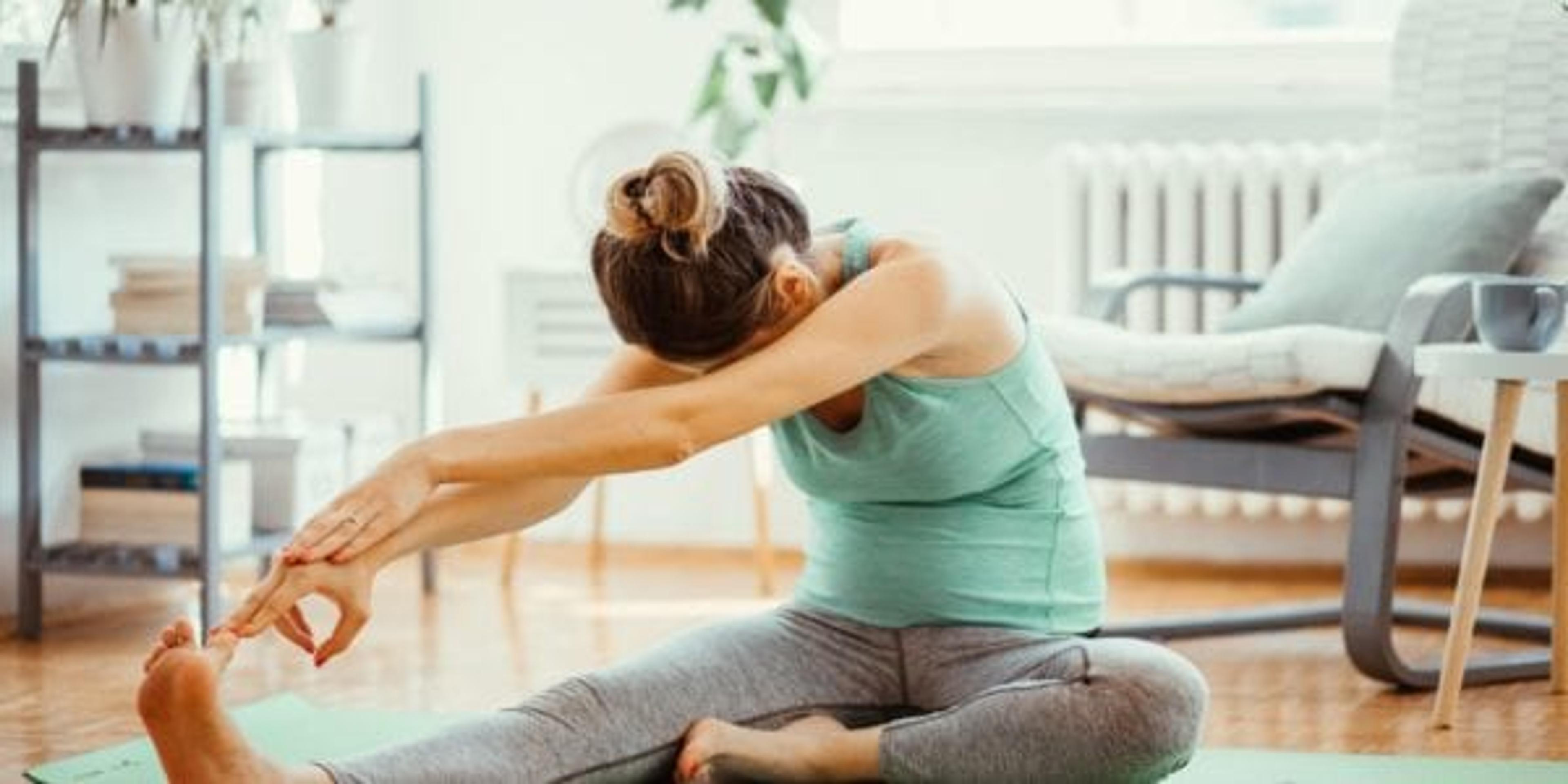 Woman working out at home with phone by her side.