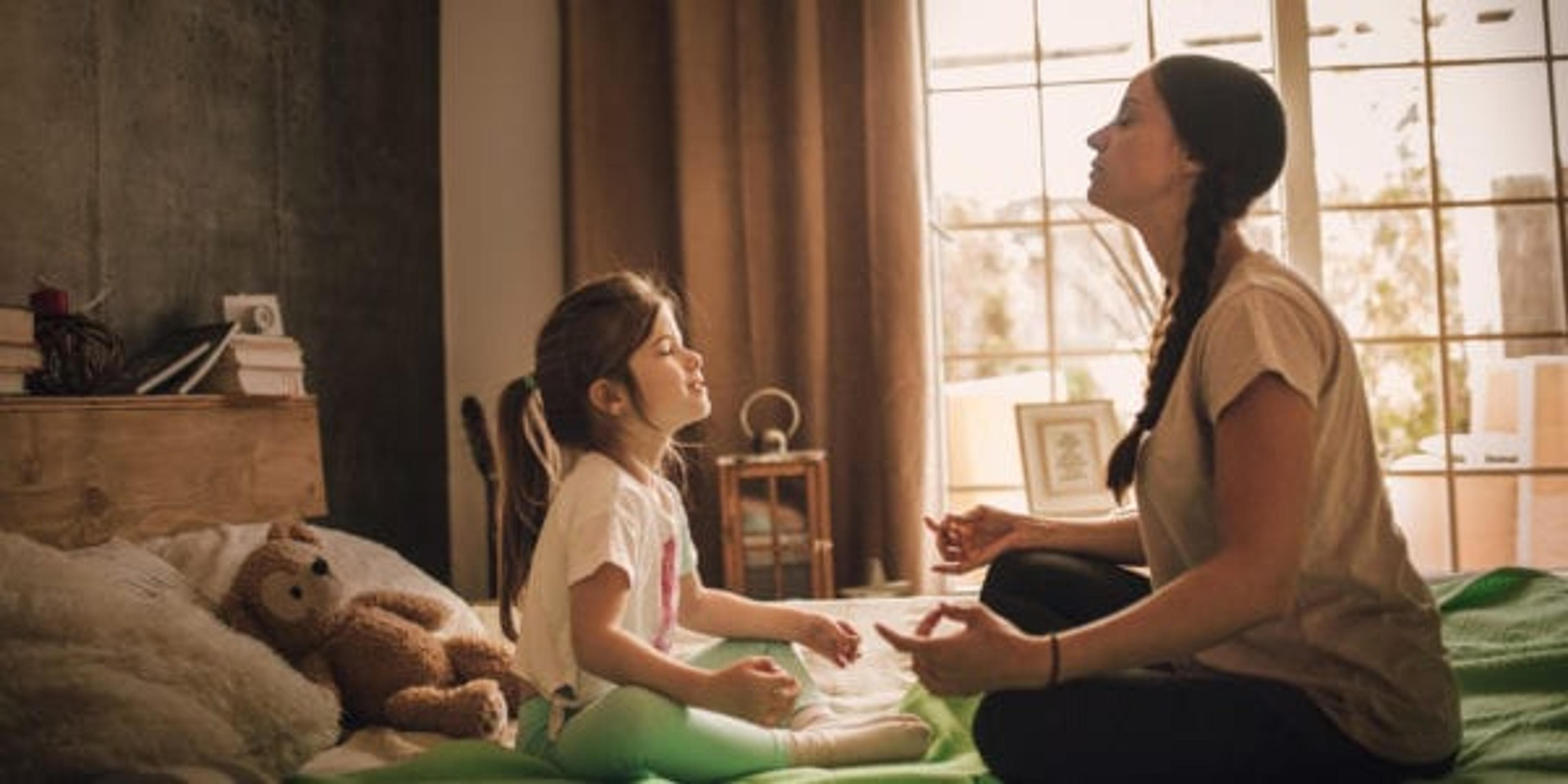Woman meditating with her daughter