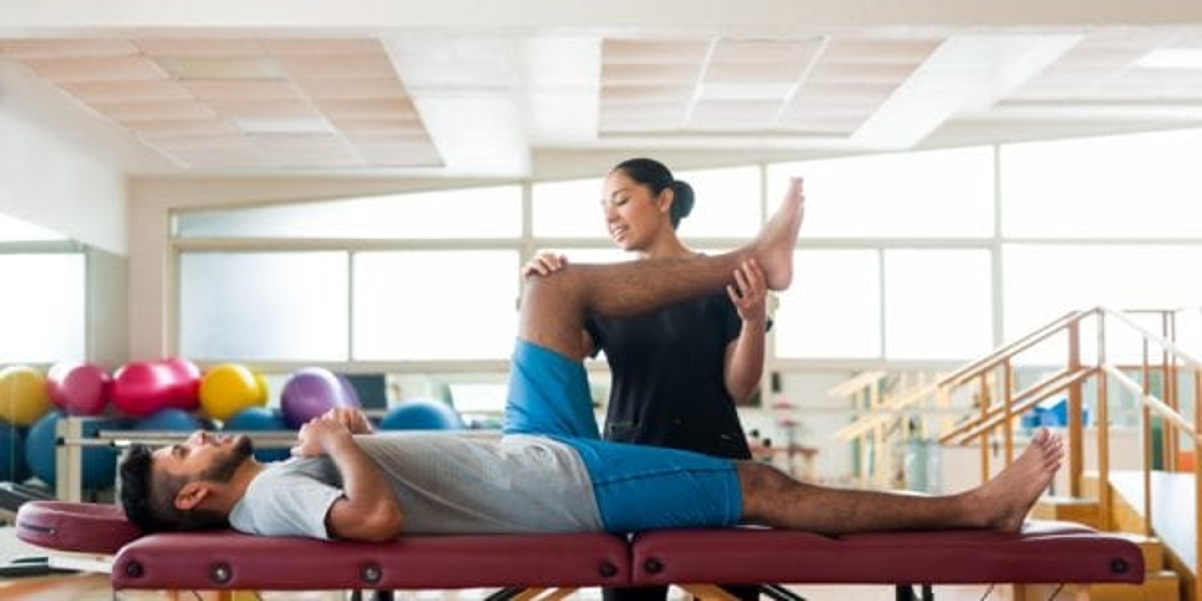 Physical therapy patient being helped by physical therapist.