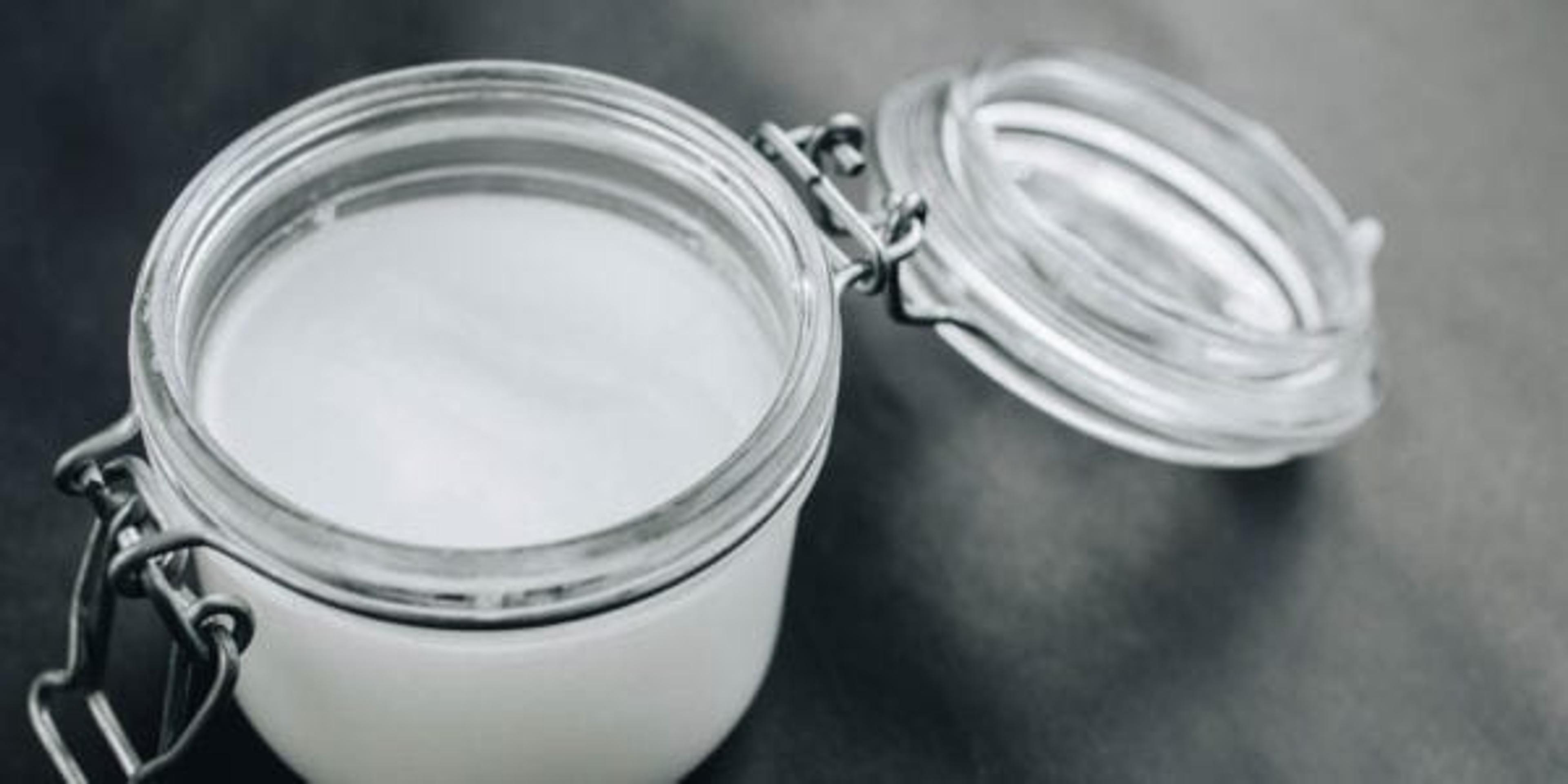 Coconut oil in a jar on dark background