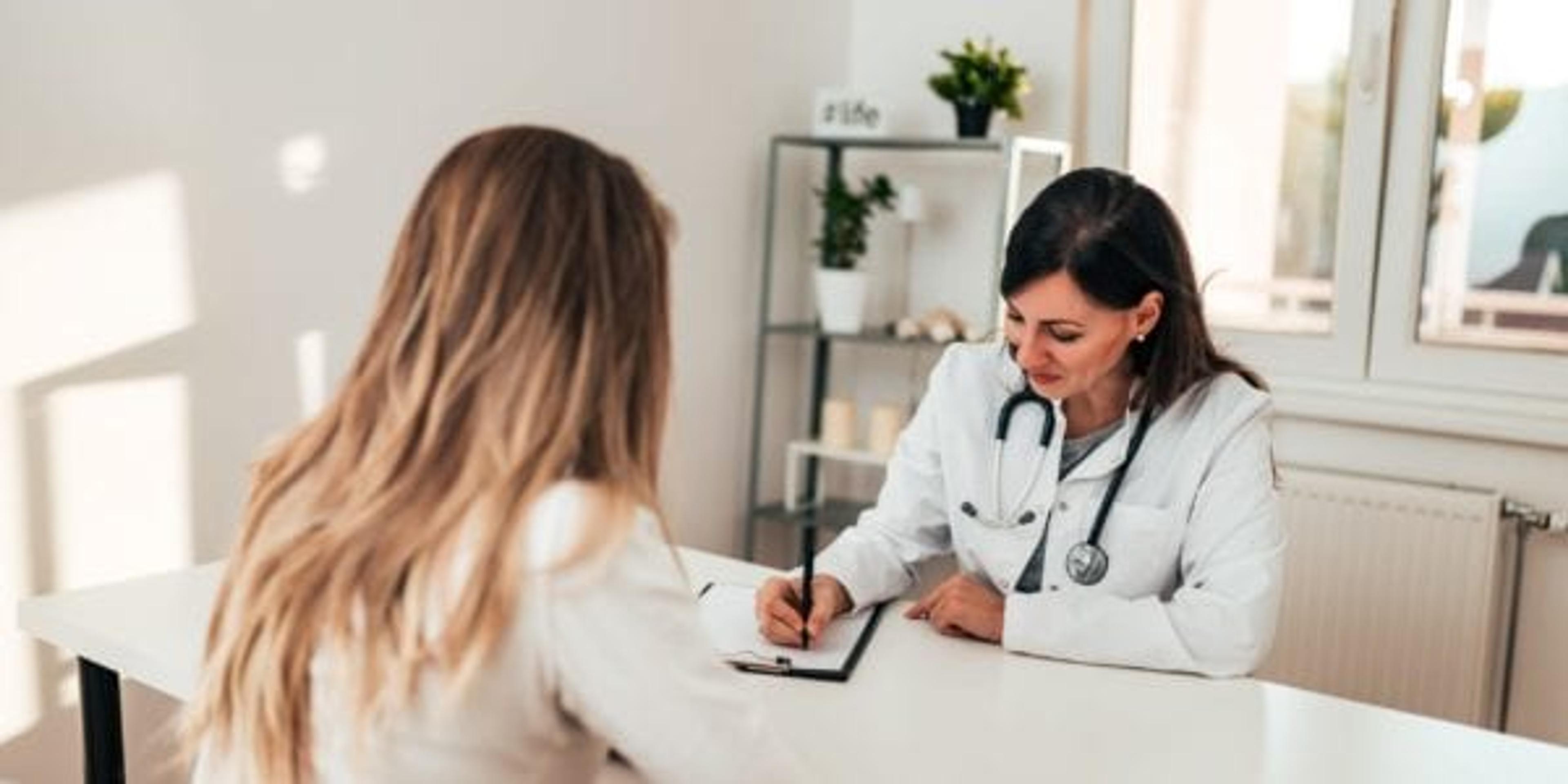 Female doctor writing a prescription for female patient