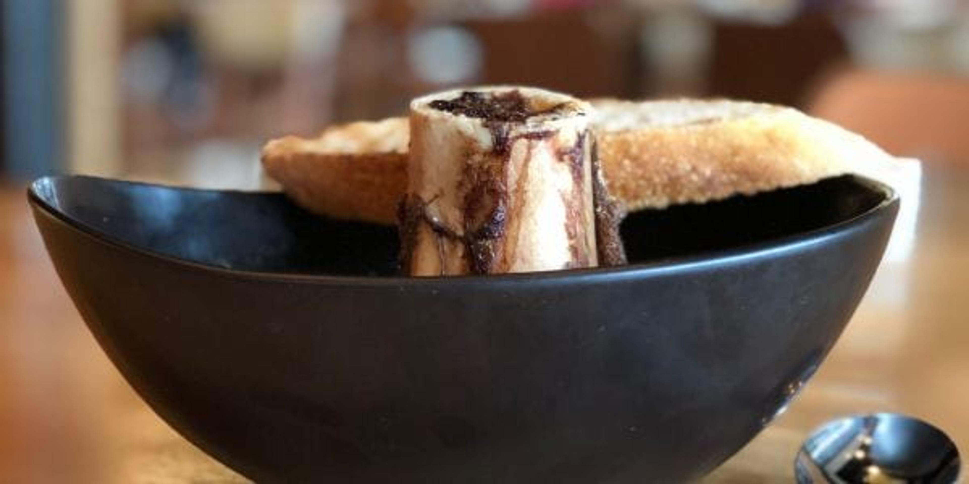 Bowl of bone broth with a bone and bread