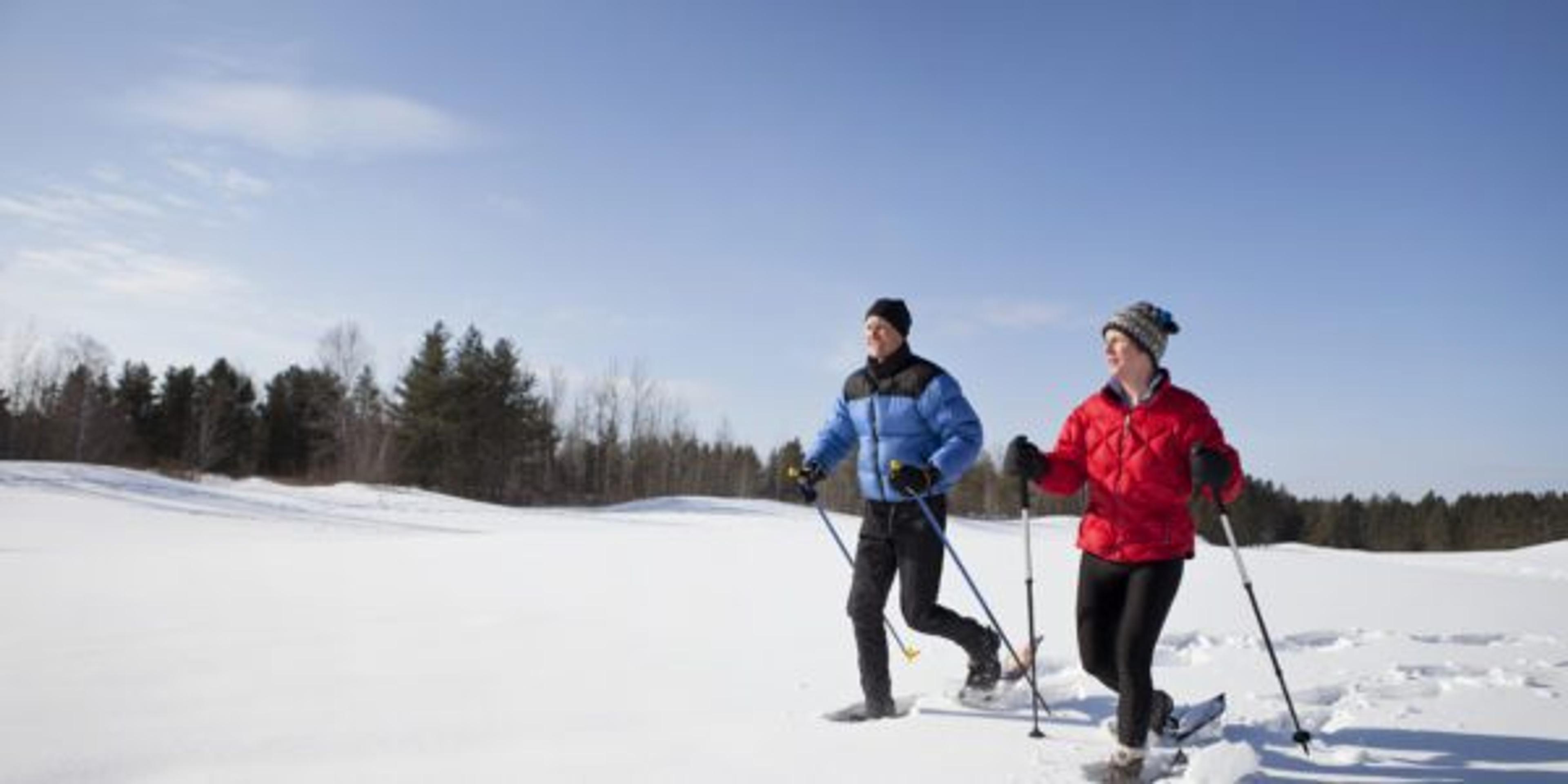 Man and Woman Snowshoeing on a Sunny Winter Day.