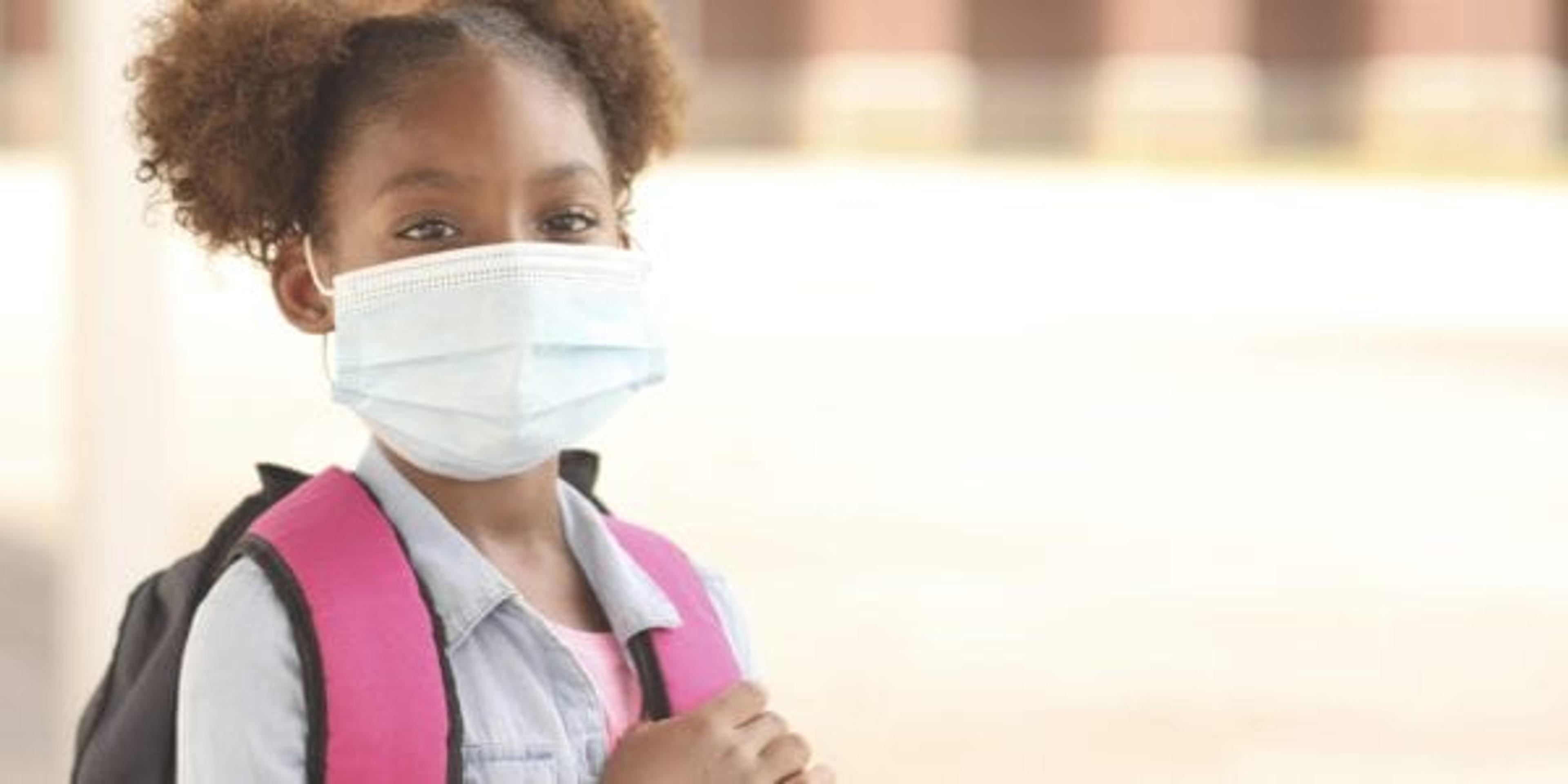 Little girl going to school with a mask on