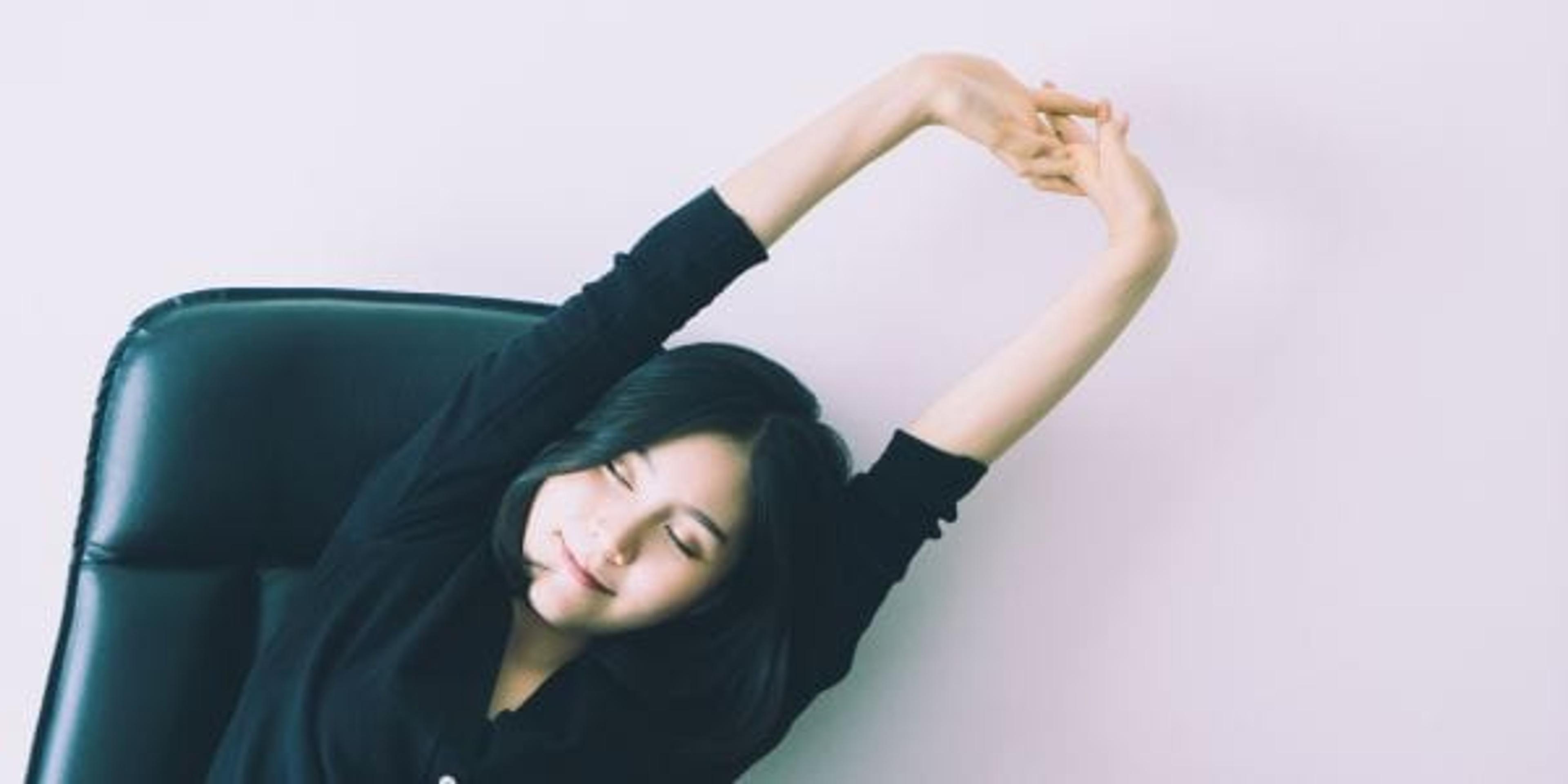 Female office worker stretching arms at her desk