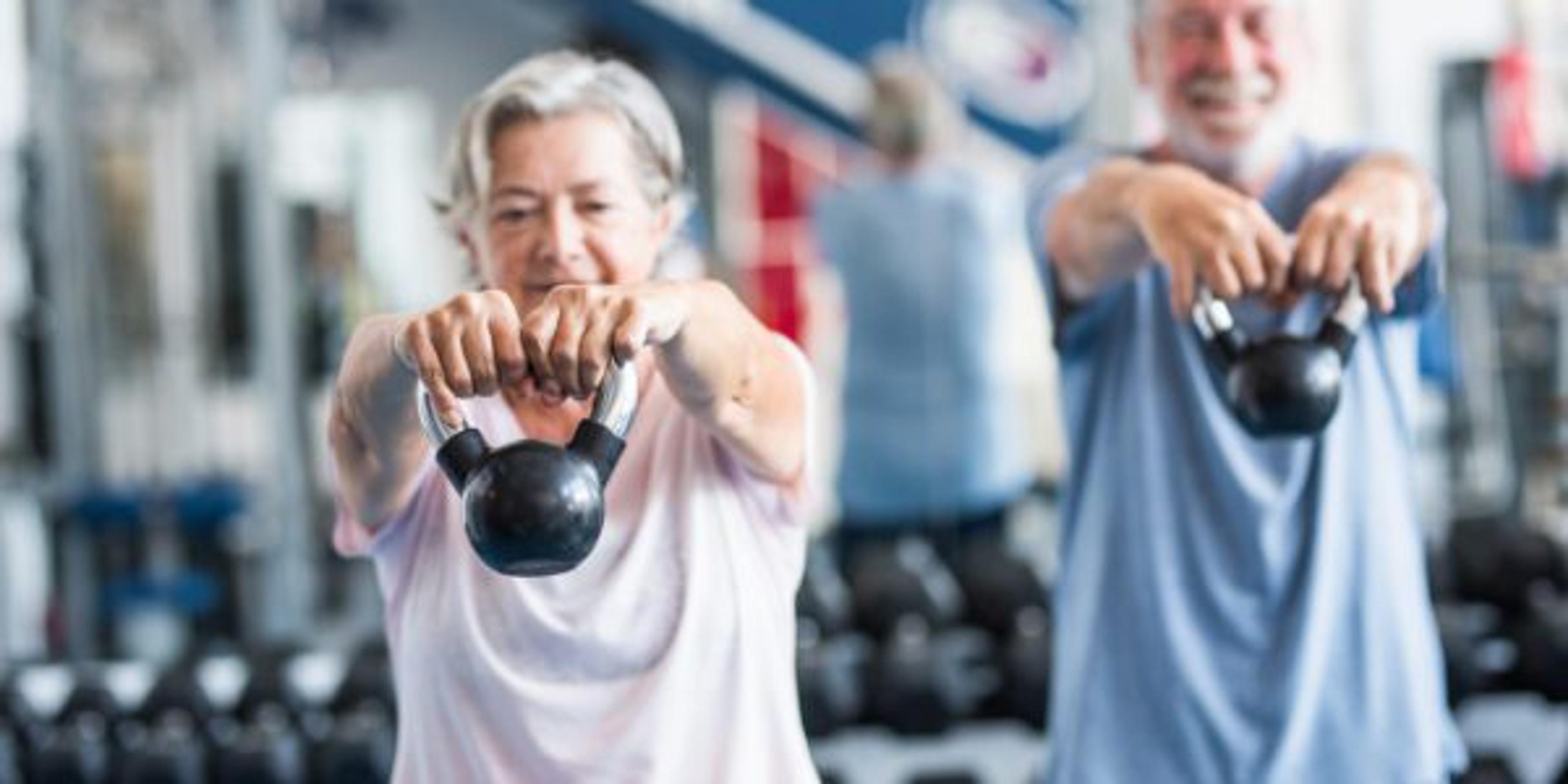 couple of two happy and fitess seniors doing exercise in the gym together running on the tapis roulant - active lifestyle