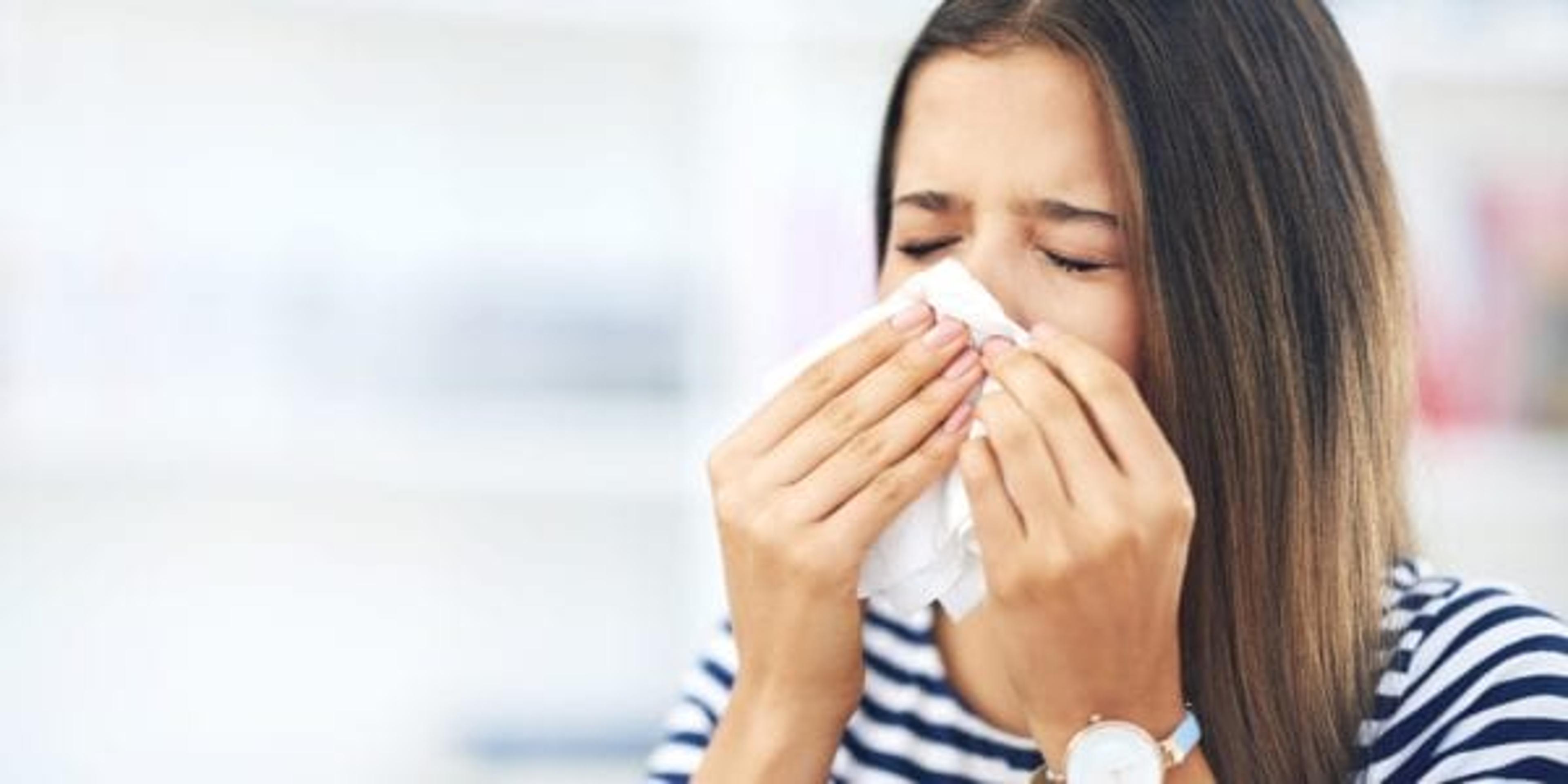 Woman sneezing into a tissue