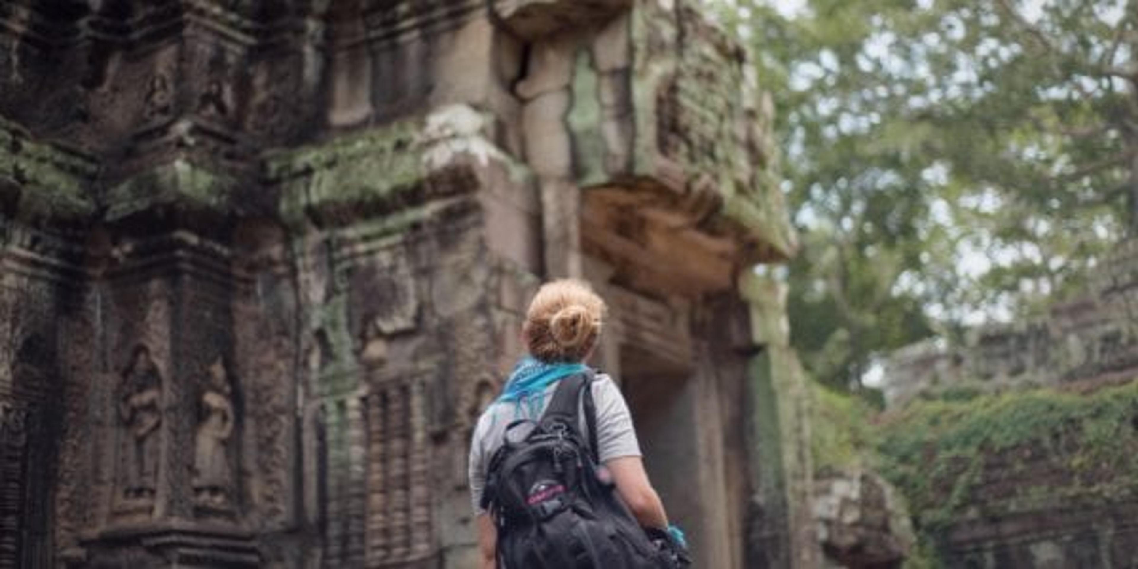 woman in front of ruined building traveling