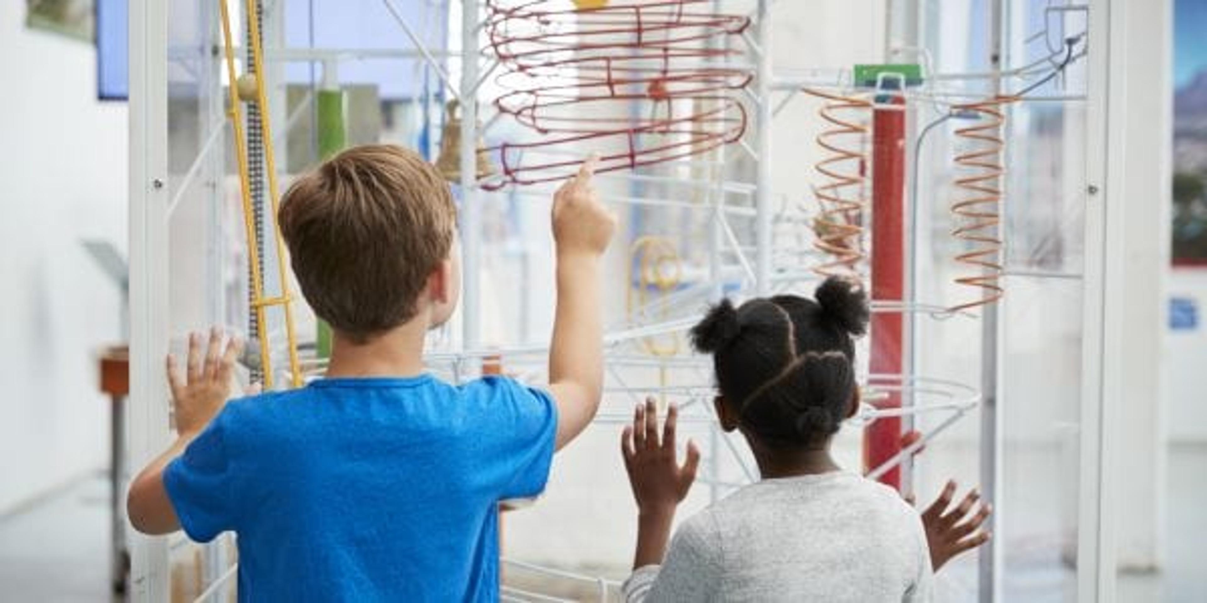 Two kids looking at a science exhibit, back view