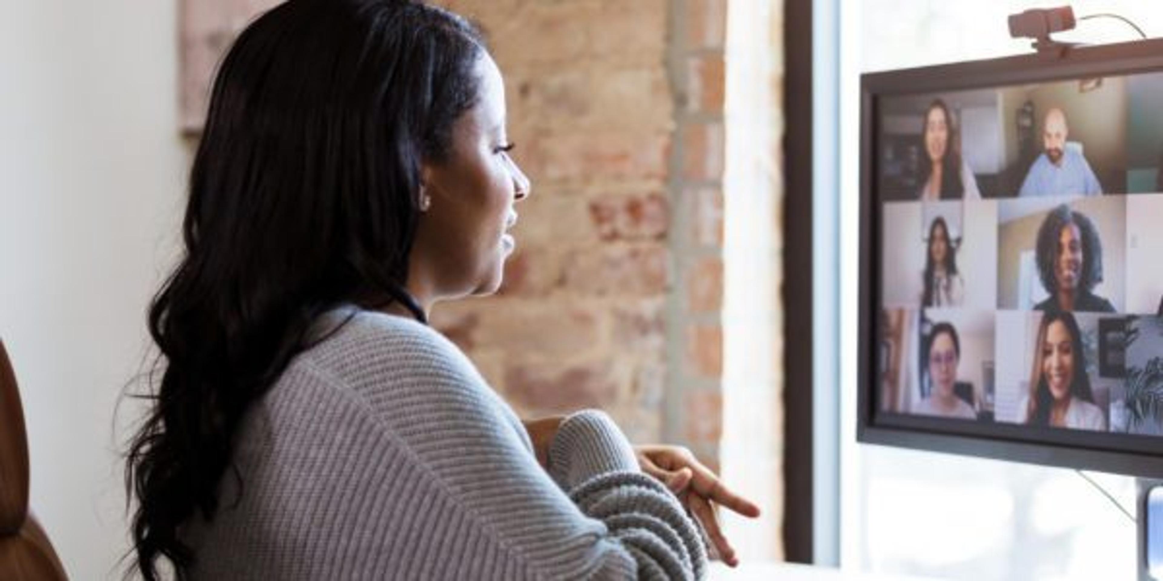 Working from home, woman meets with colleagues via video conference