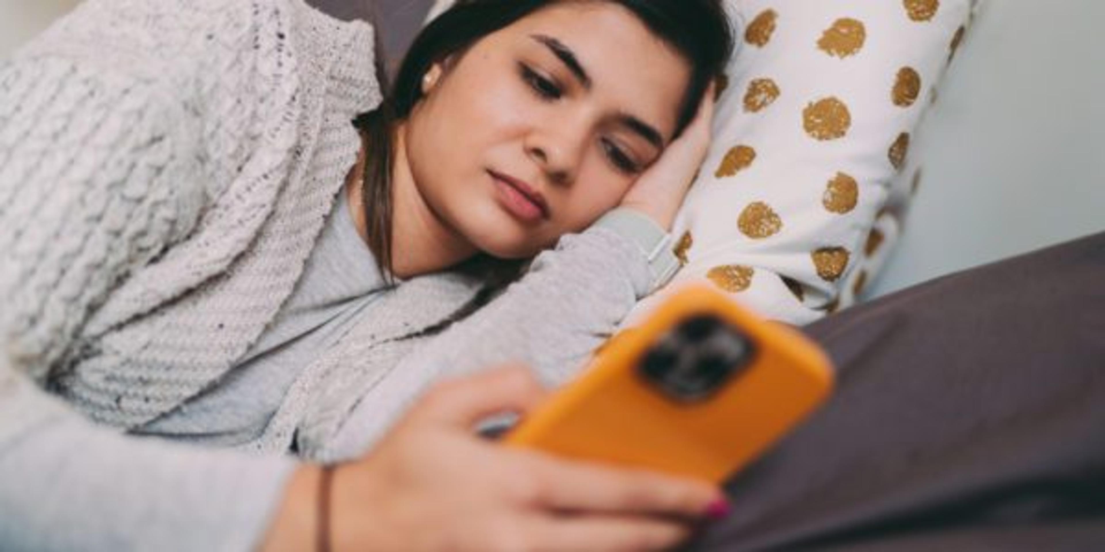 Woman in bed texting on phone