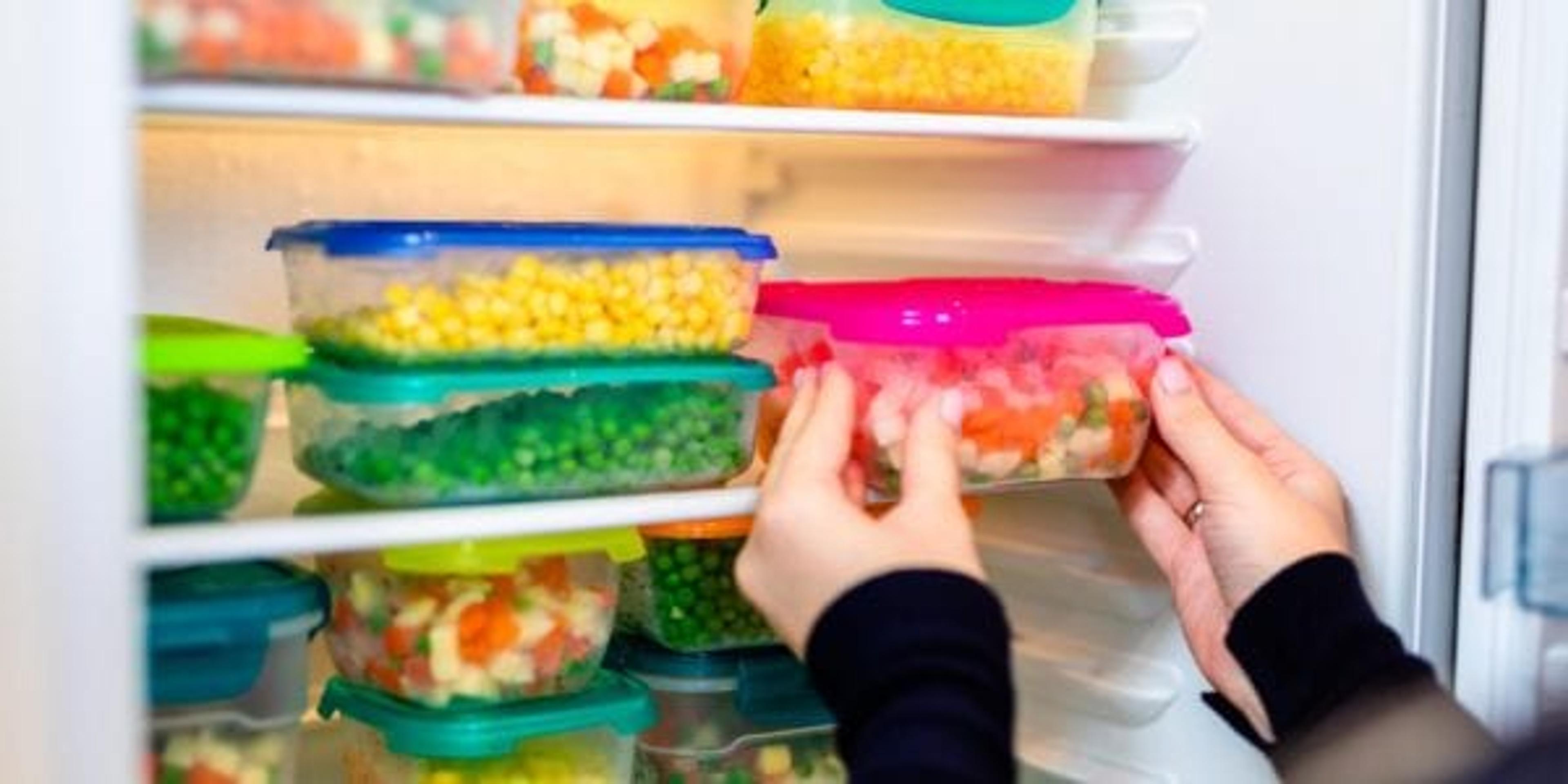 Woman putting storage containers of food in fridge