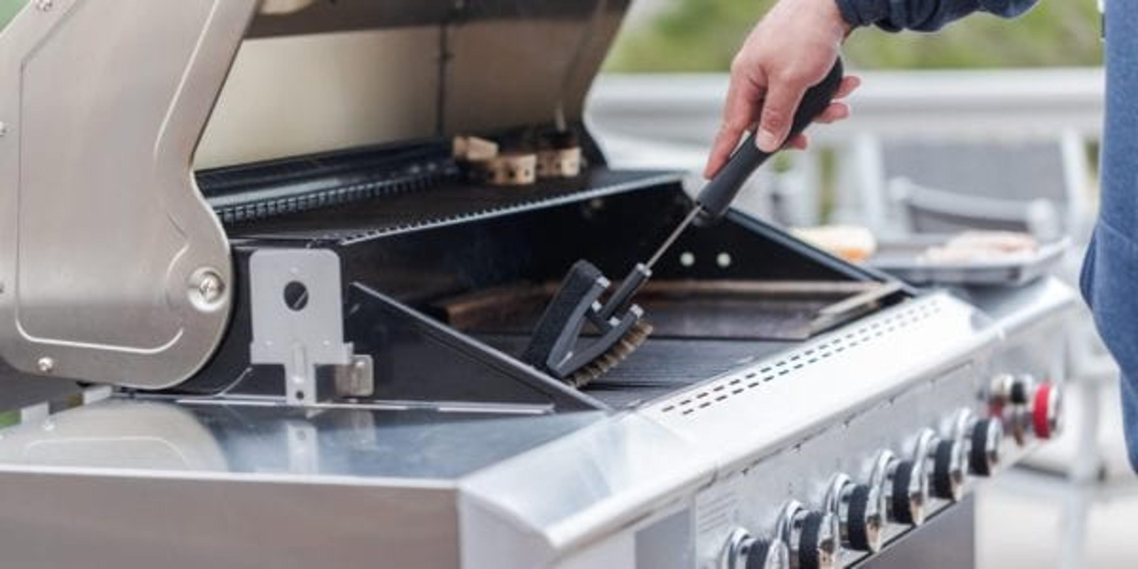 Man using a scrub brush to clean grill