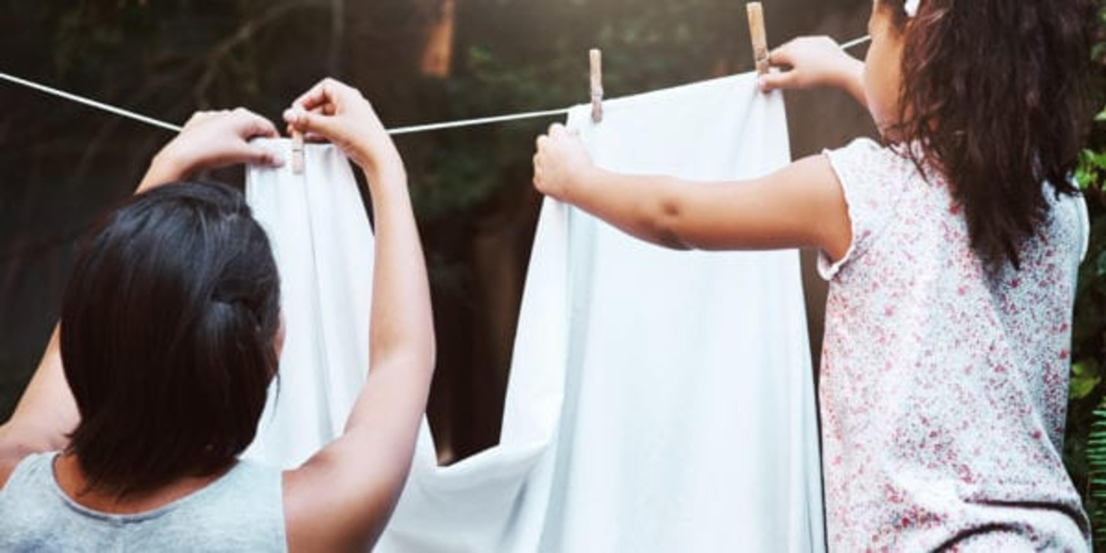 Shot of a mother and her little daughter hanging up laundry on a washing line outdoors