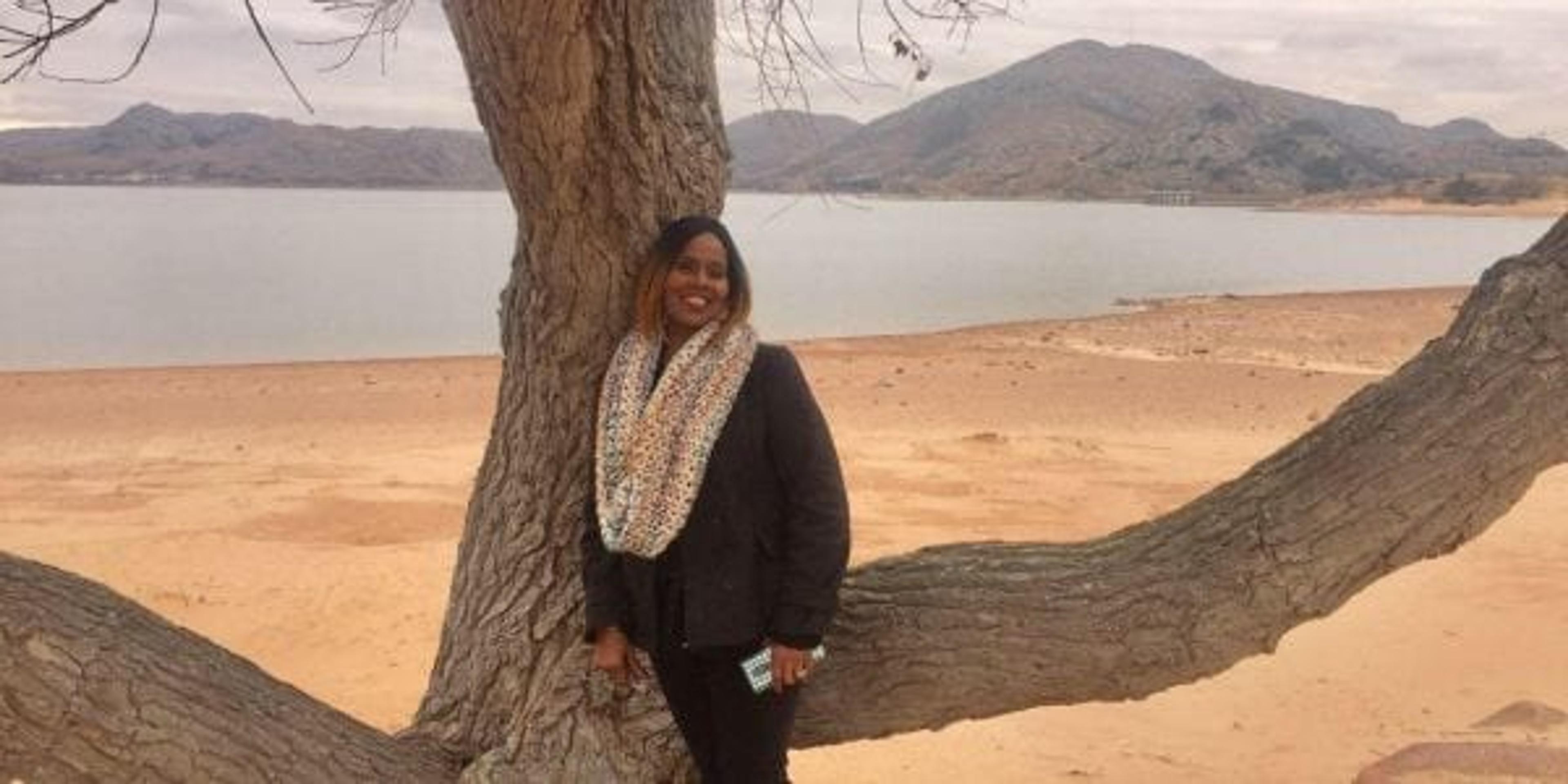 Rosalind Davis posing in front of a tree on the beach.