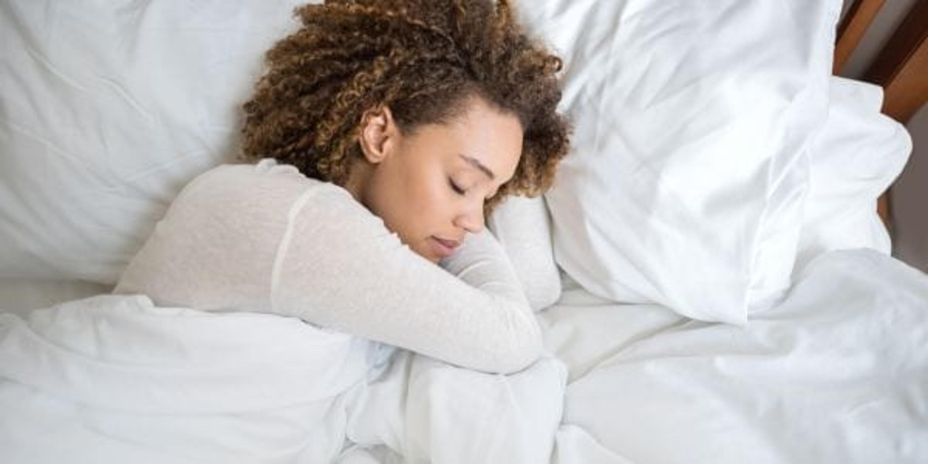 Woman sleeping under a heavy blanket.