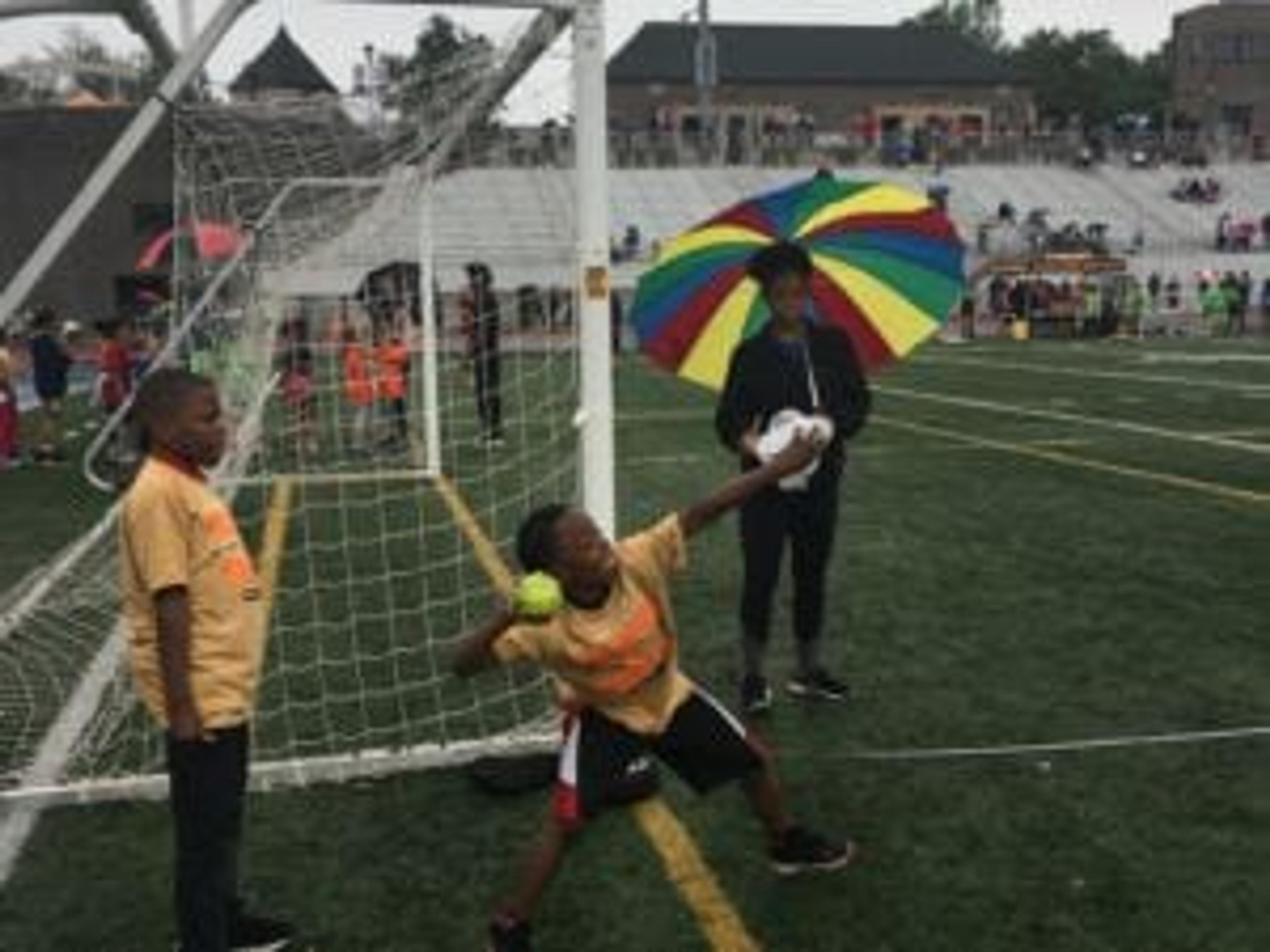 A young Grand Rapids Public Schools athlete winds his arm back to throw the shot put at a track meet.