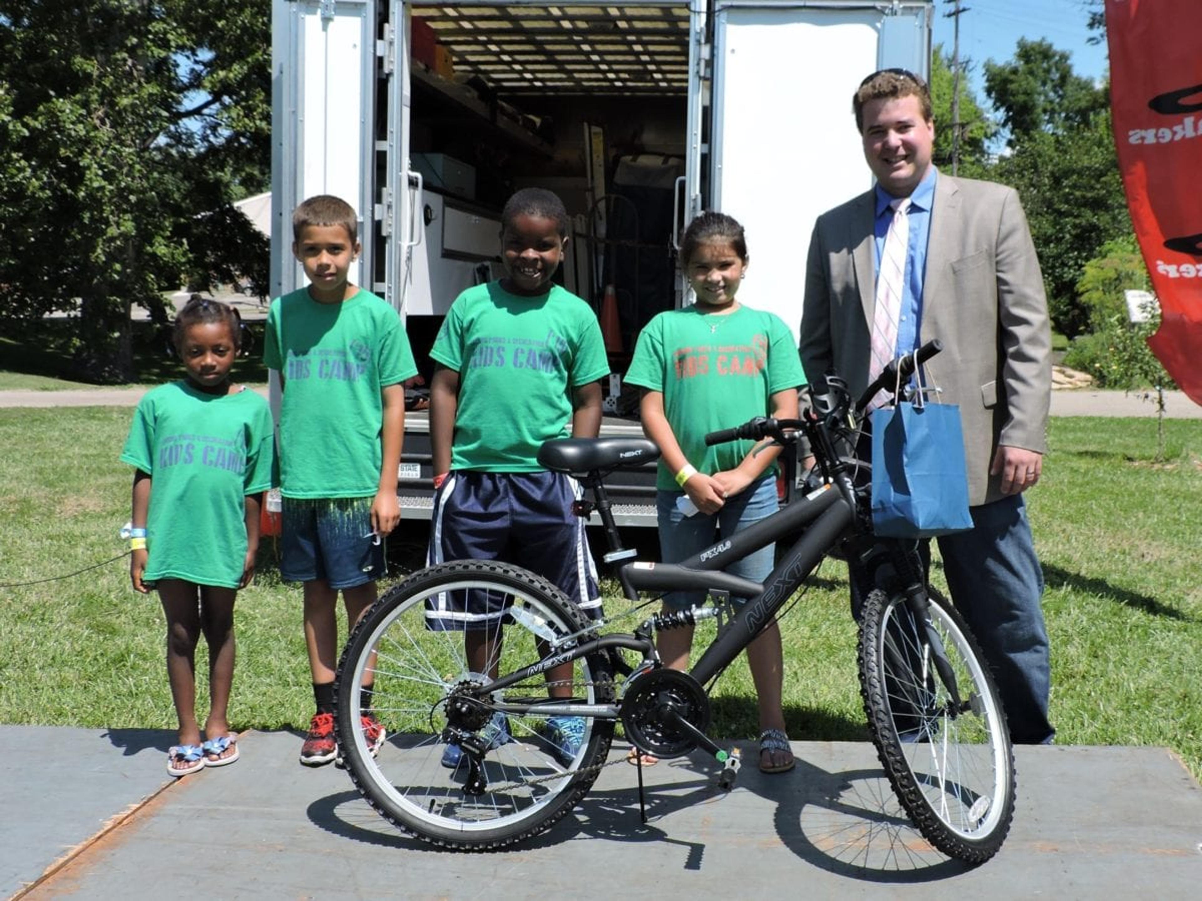 Four bicycle winners pose with BCBSM Senior Community Relations Liaison B.J. Puchala.