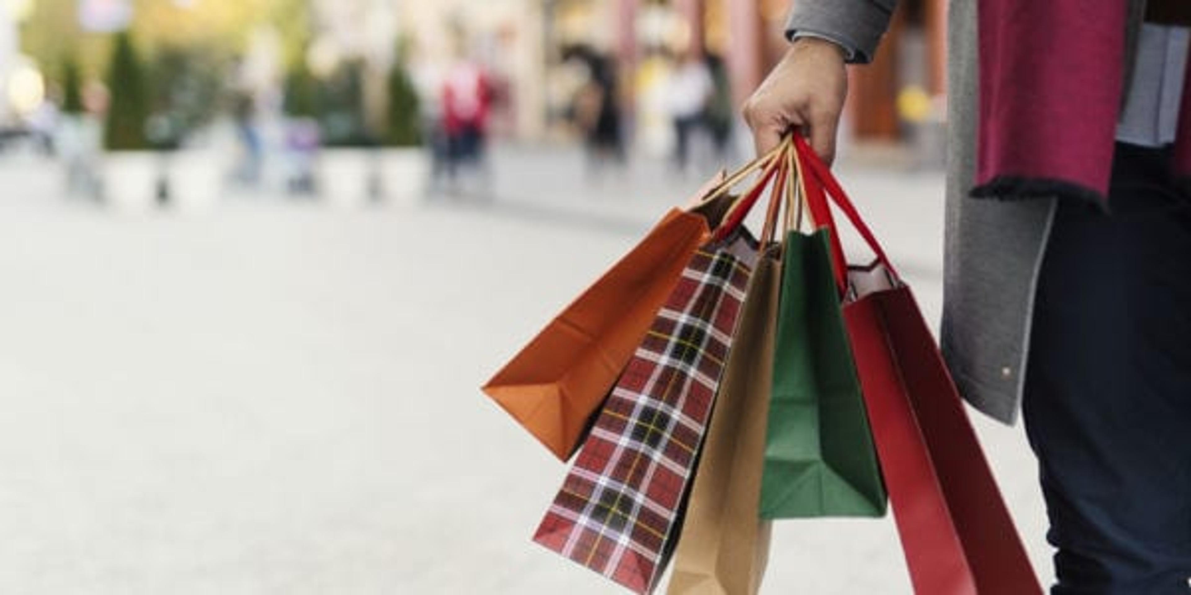 Image of man holding shopping bags with presents on the street.
