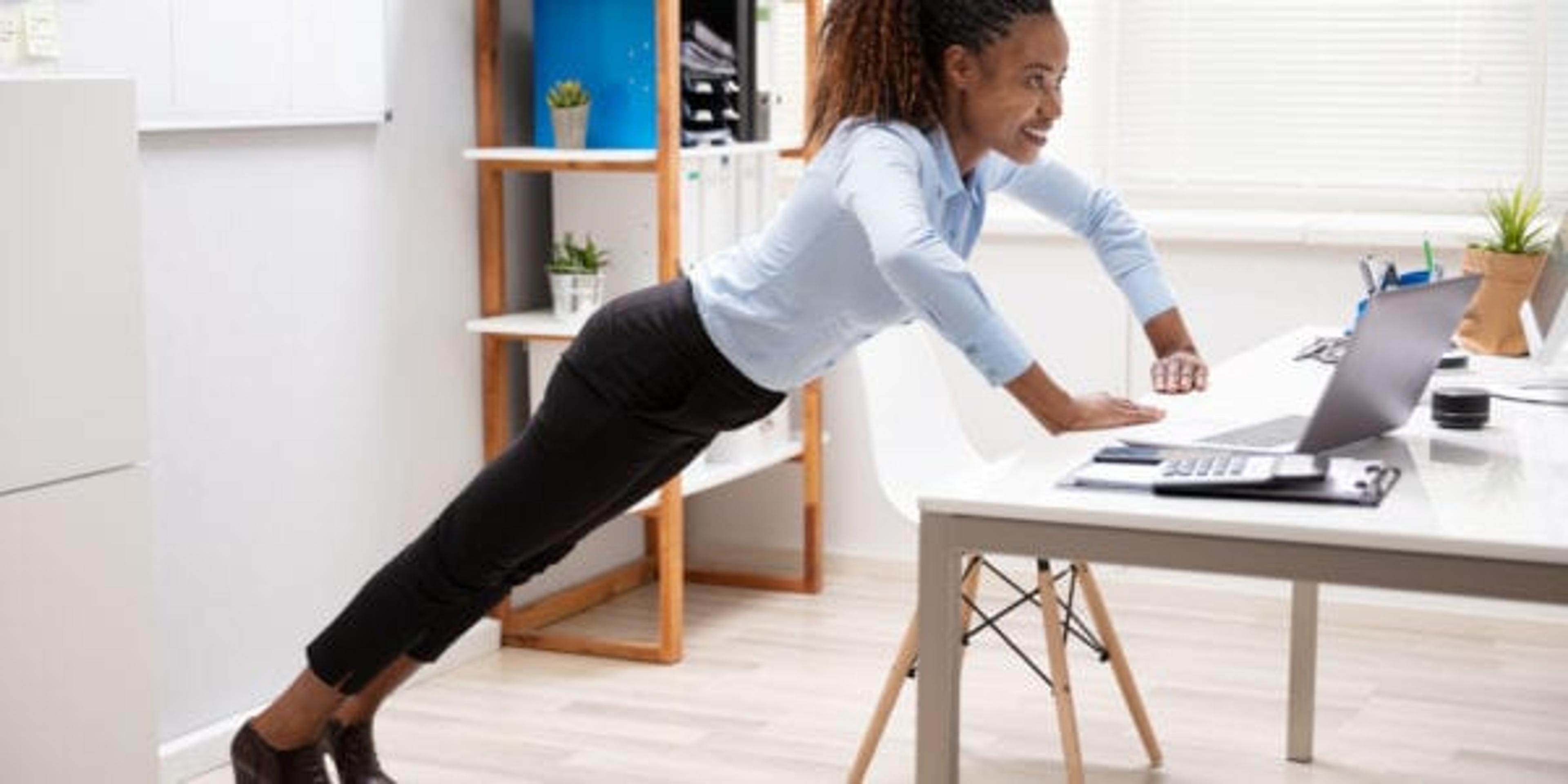 Side View Of A Happy Young Businesswoman Doing Push Up At Workplace