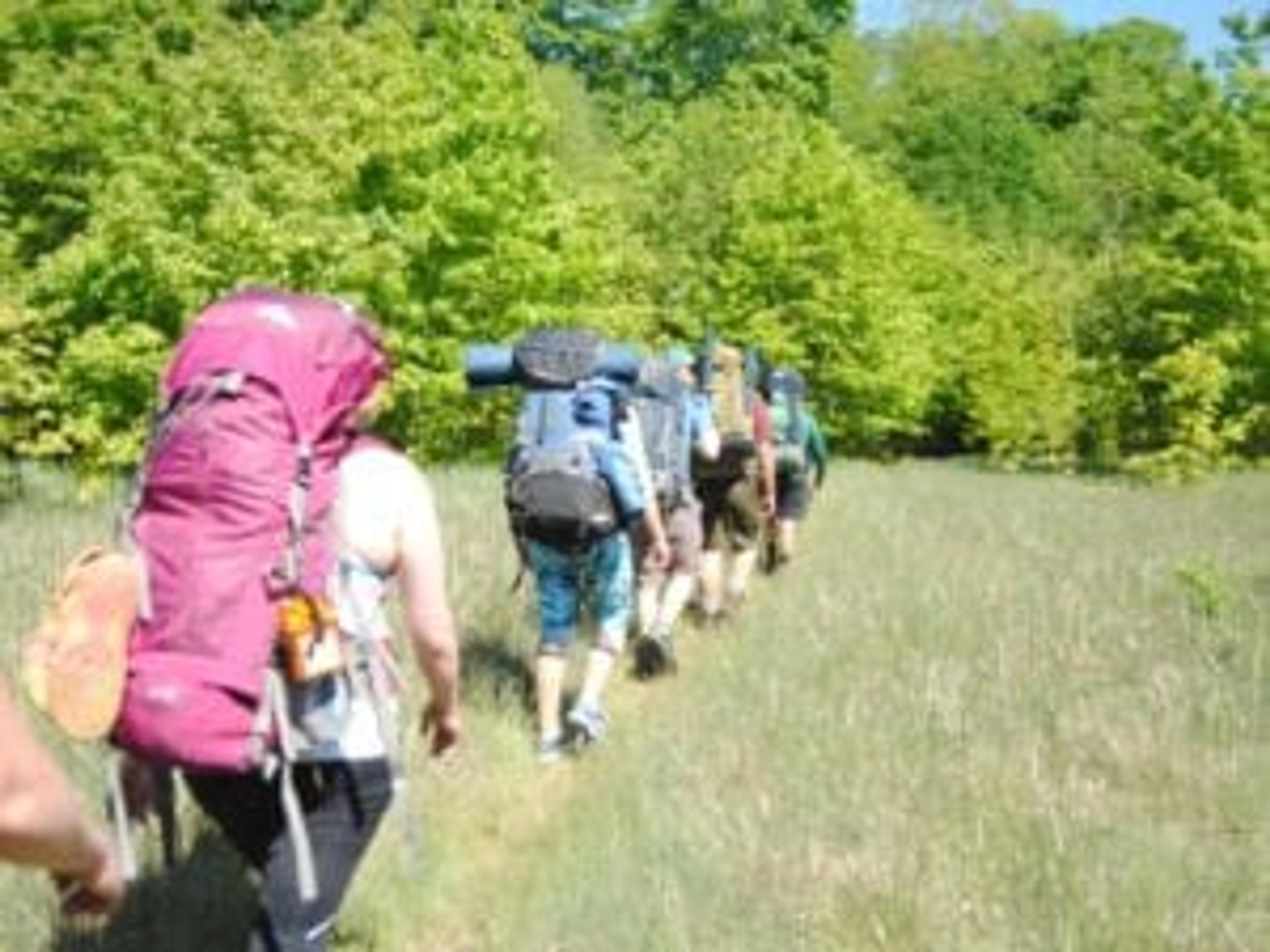 the group with backpacks walking in a field