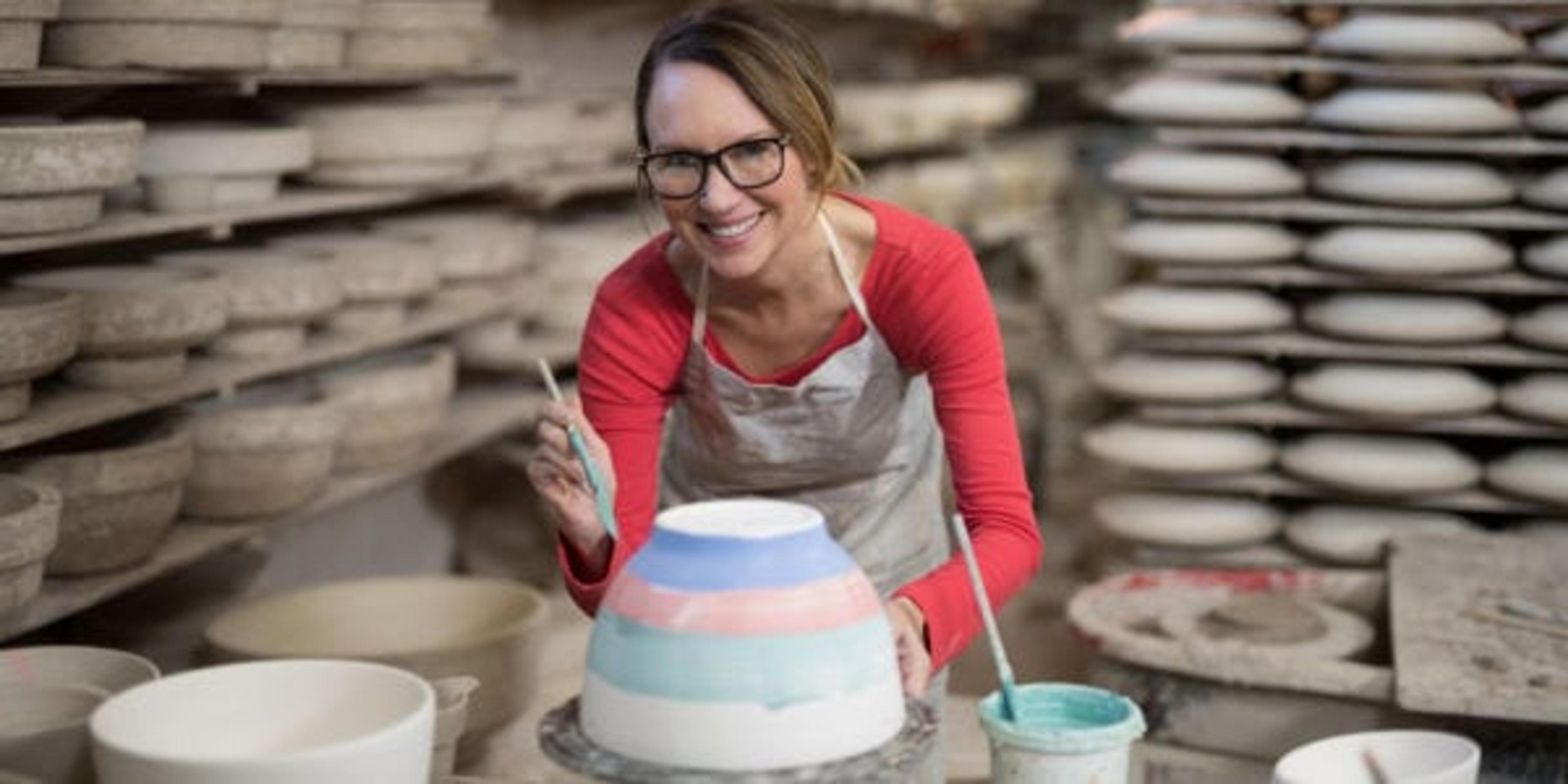 Portrait of female potter painting bowl in pottery workshop