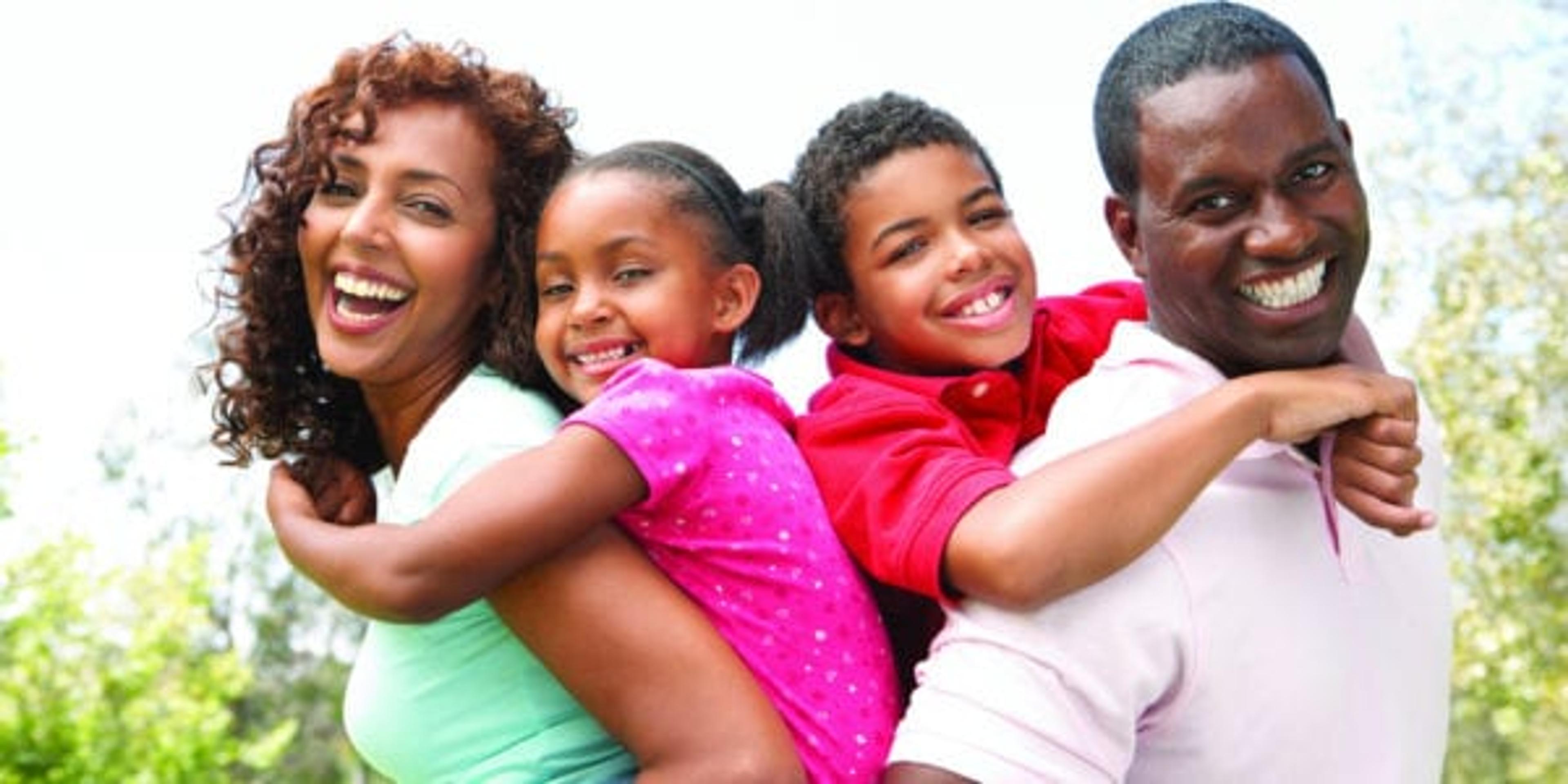 A black mother and father with a son and daughter smiling.