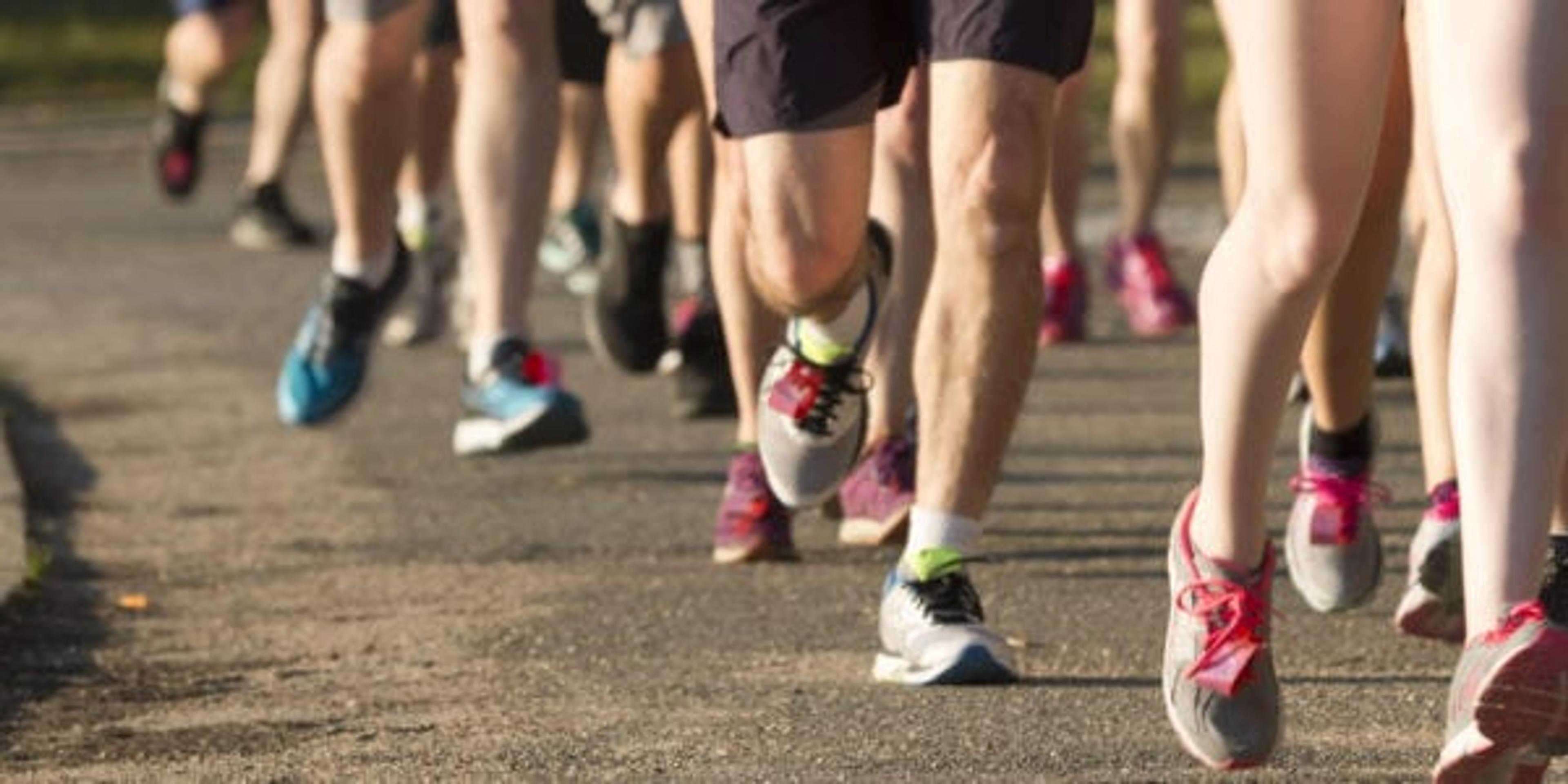 Runners racing a local 5K around a lake on a dirt path on a early summer evening.