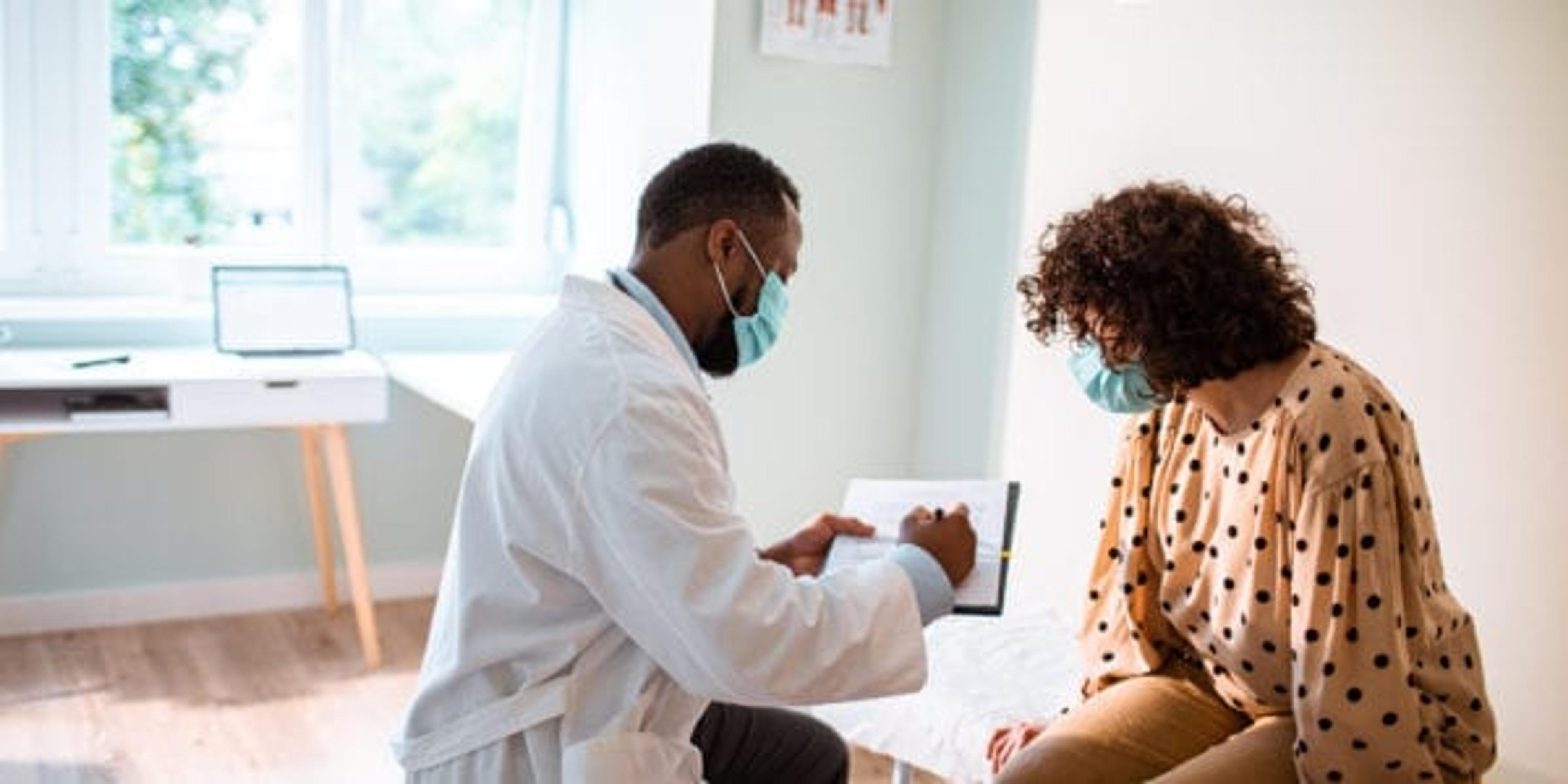 Close up of a doctor doing a medical exam while both him and the patient are wearing protective masks