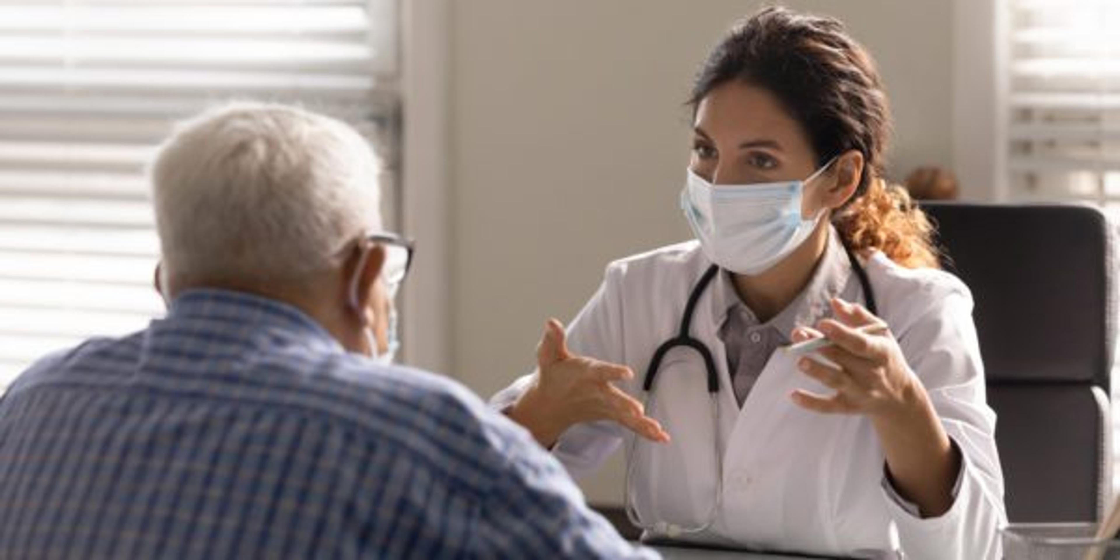 Female doctor wearing a mask speaks to a patient about colon health