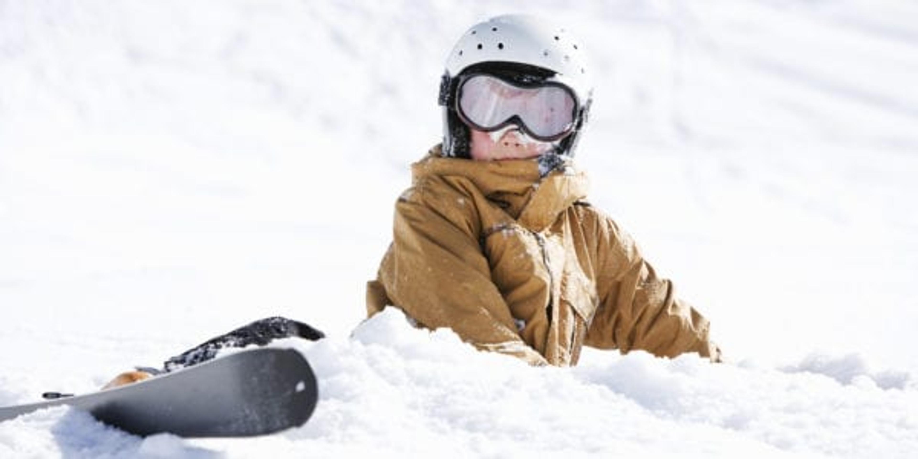 Young boy covered in snow with skis