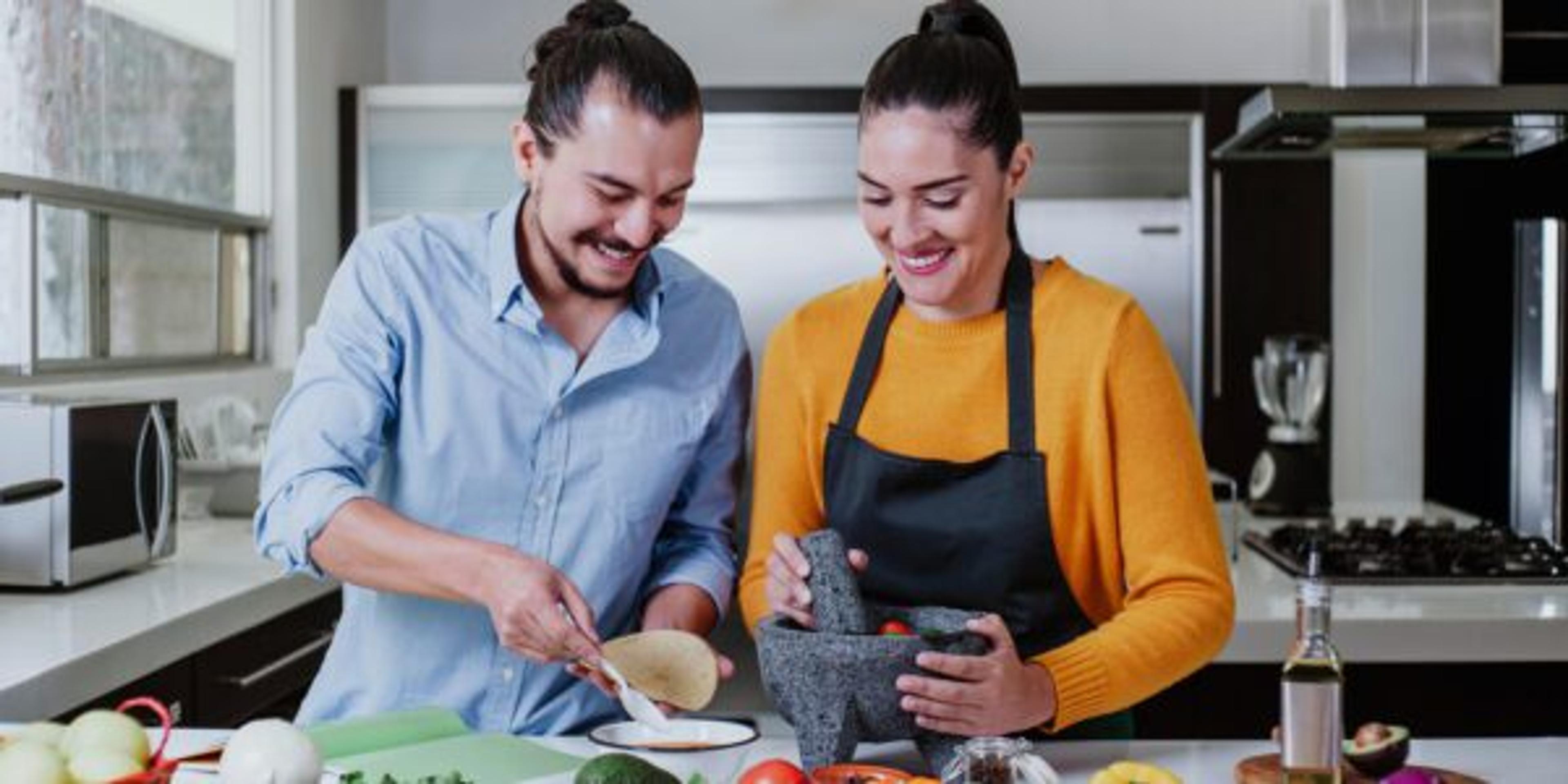 latin couple cooking mexican sauce together in their kitchen at home in Mexico city