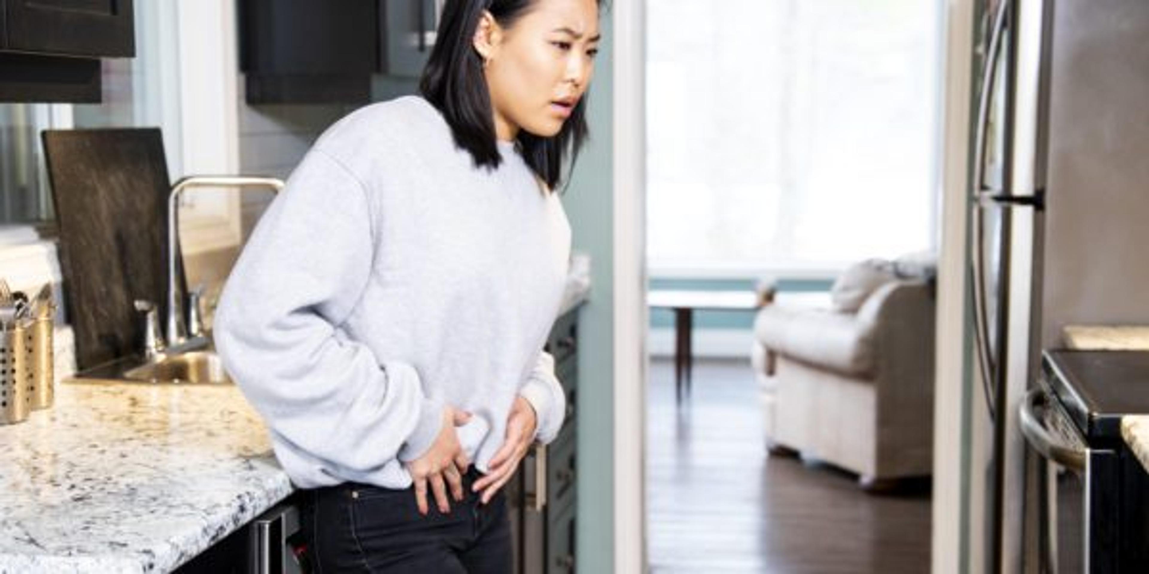 A young woman experiencing pelvic discomfort, she is grimacing in pain.