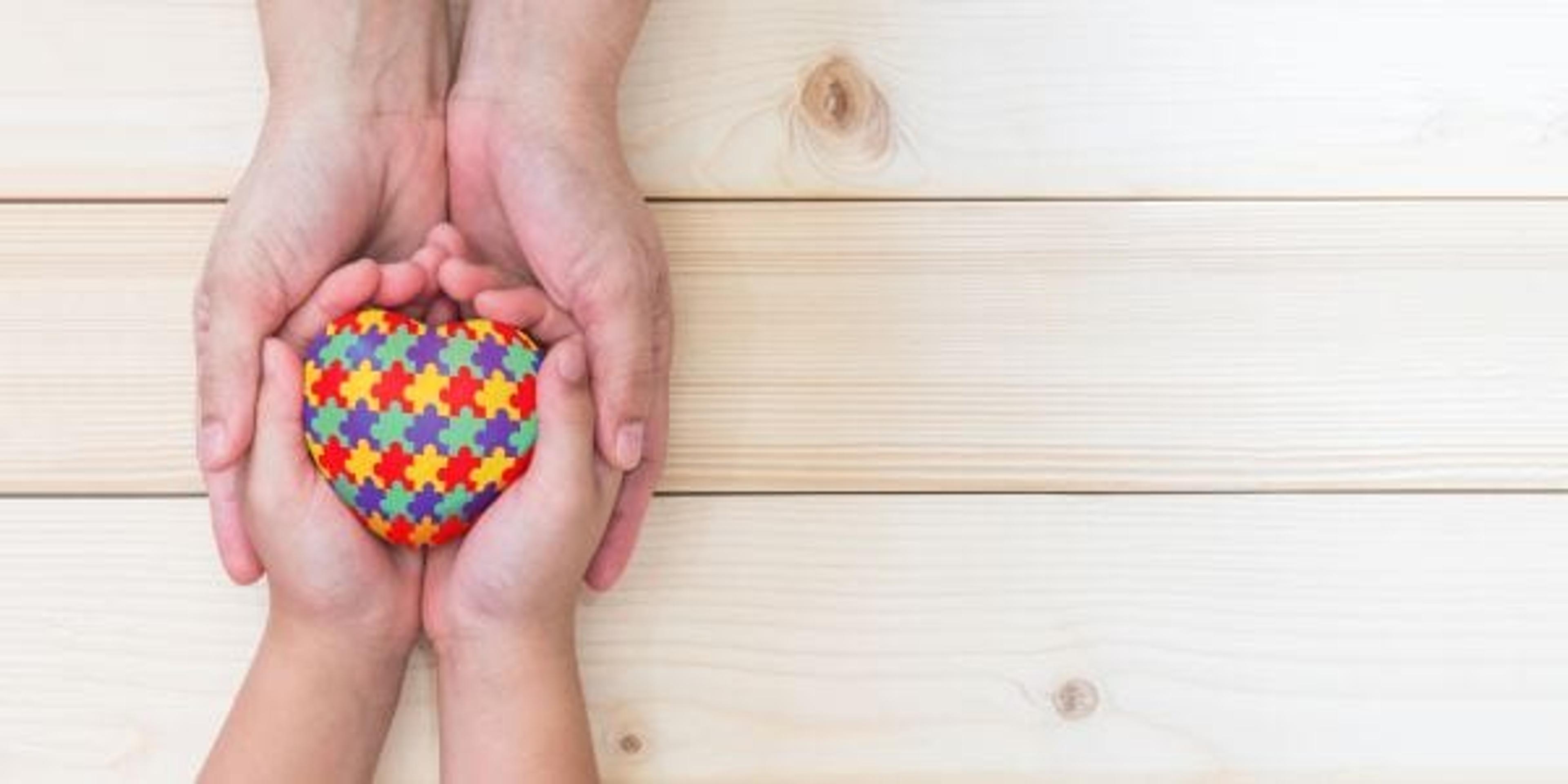 World Autism Awareness day concept with puzzle or jigsaw pattern on heart with autistic child's hands supported by nursing family caregiver