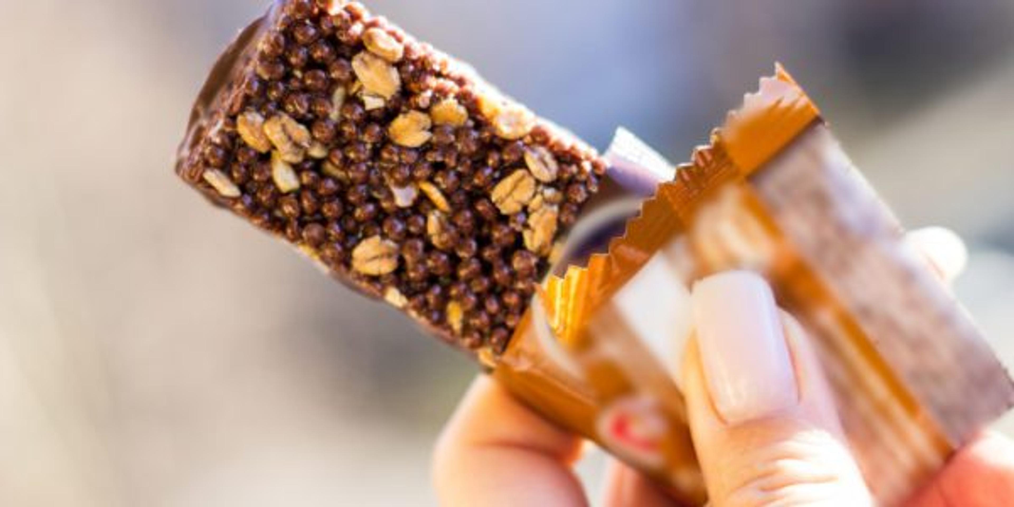 Hand holding a half-unwrapped granola bar.