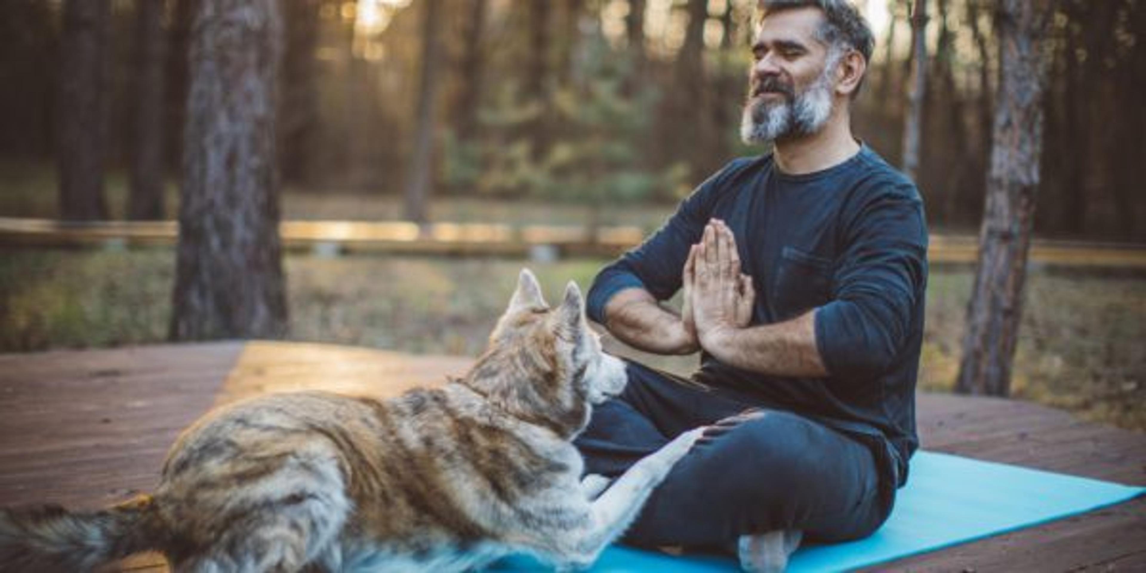 Man going through andropause doing backyard yoga at home with dog
