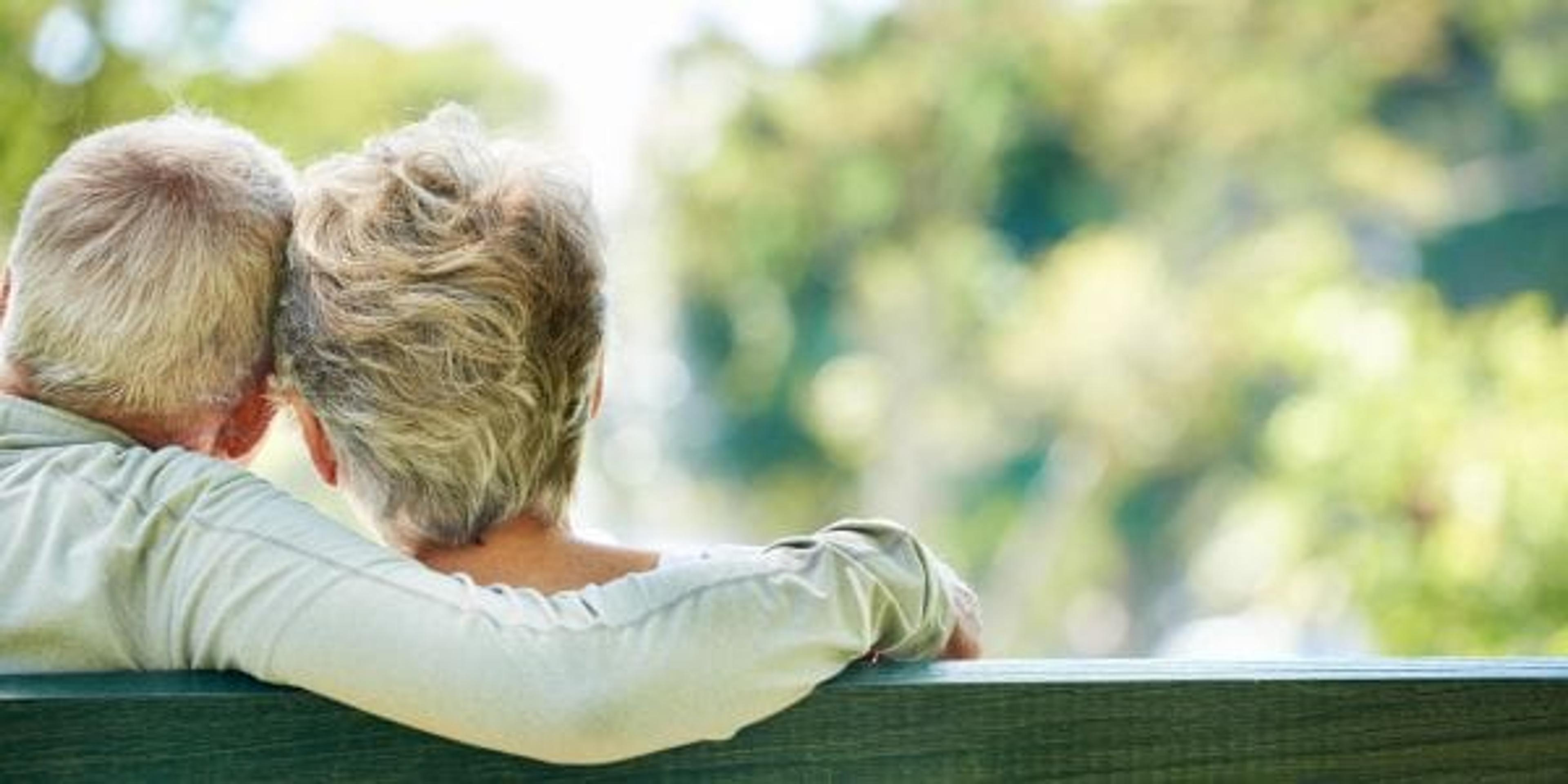 Older man and woman sitting on a park bench