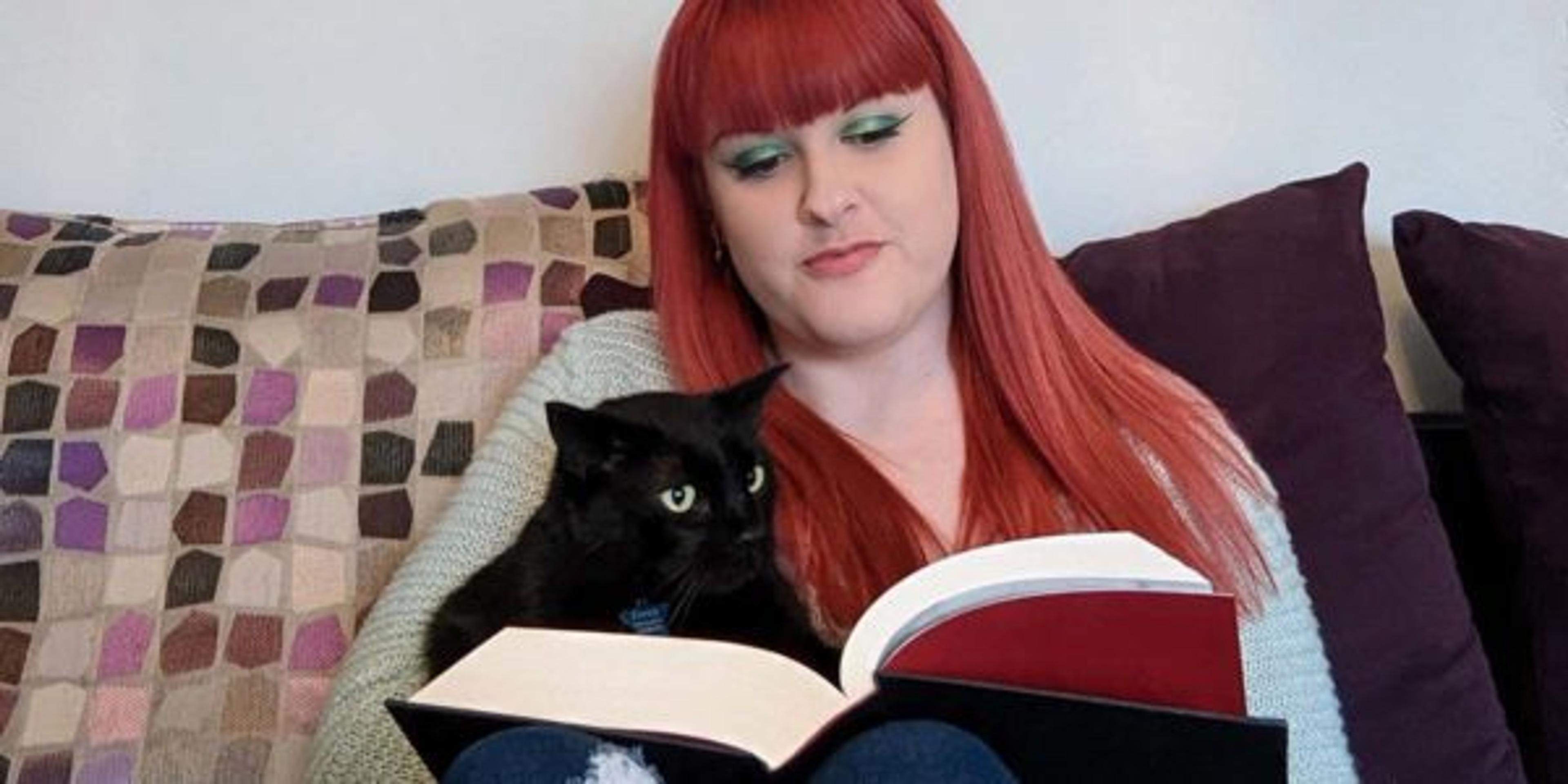 Monica Drake reads at home with her cat.