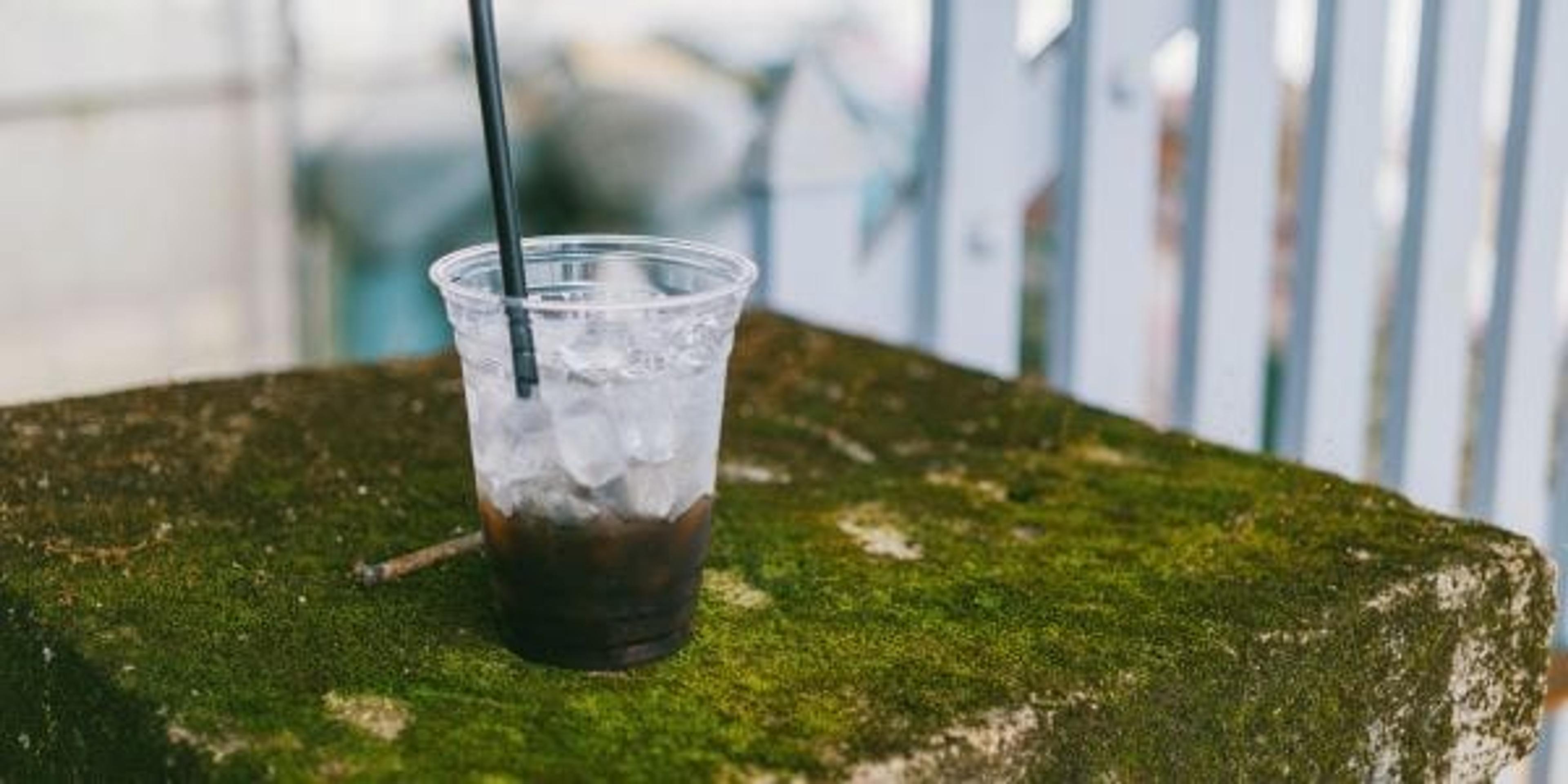 A half-empty coffee drink in a plastic cup with a plastic straw