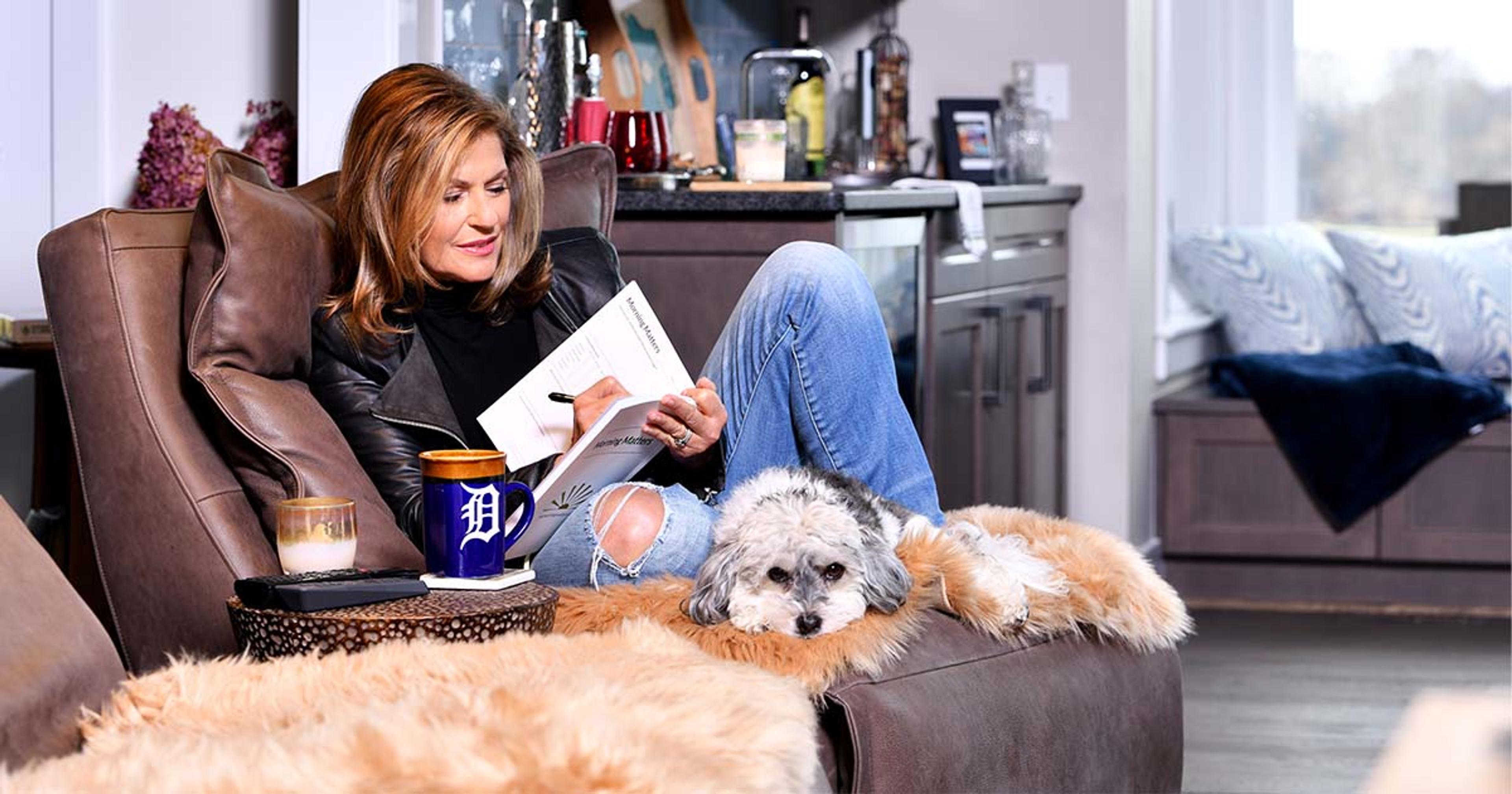 Woman journals on the couch with her dog.