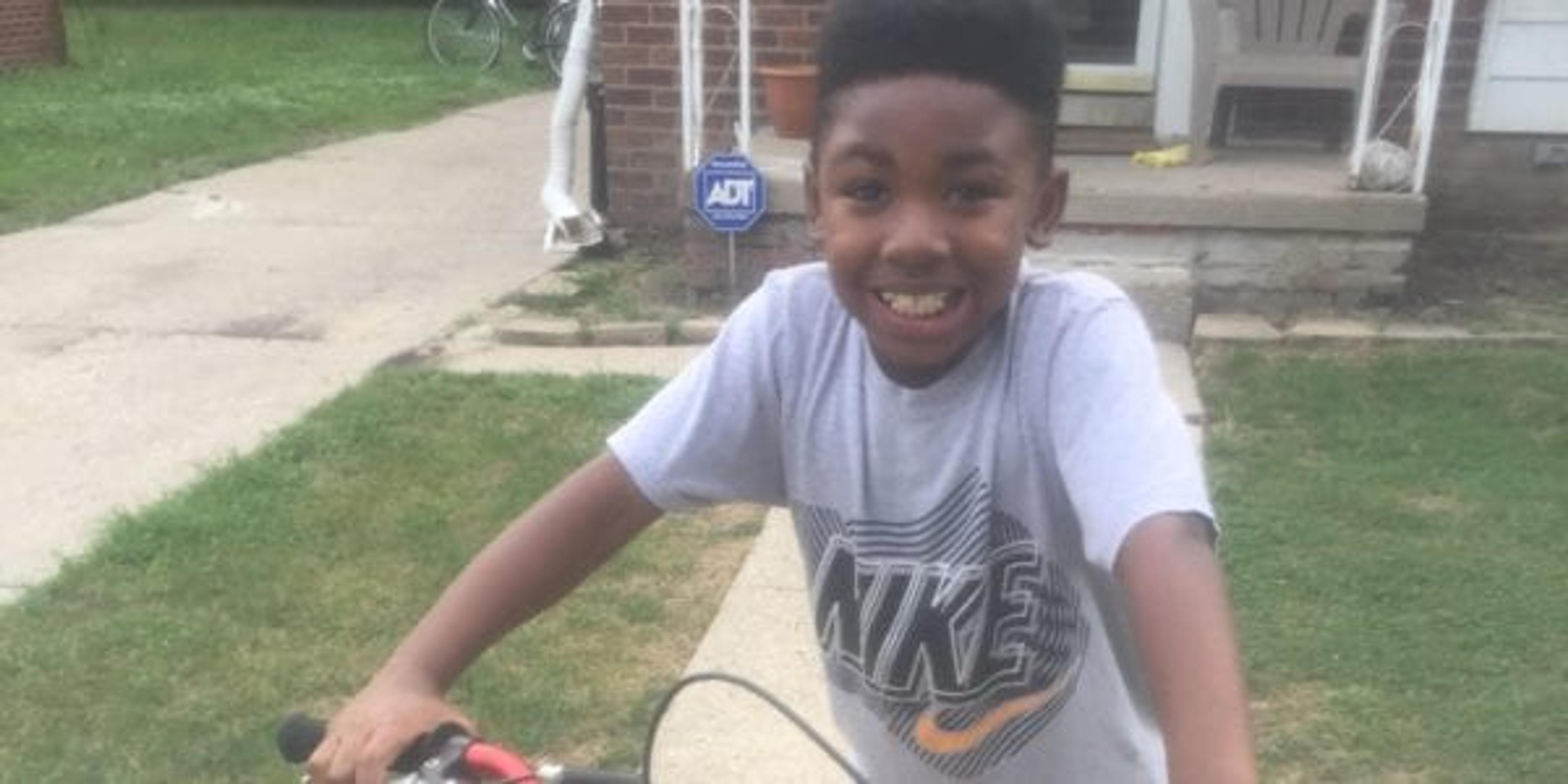 child smiling while sitting on a bike.