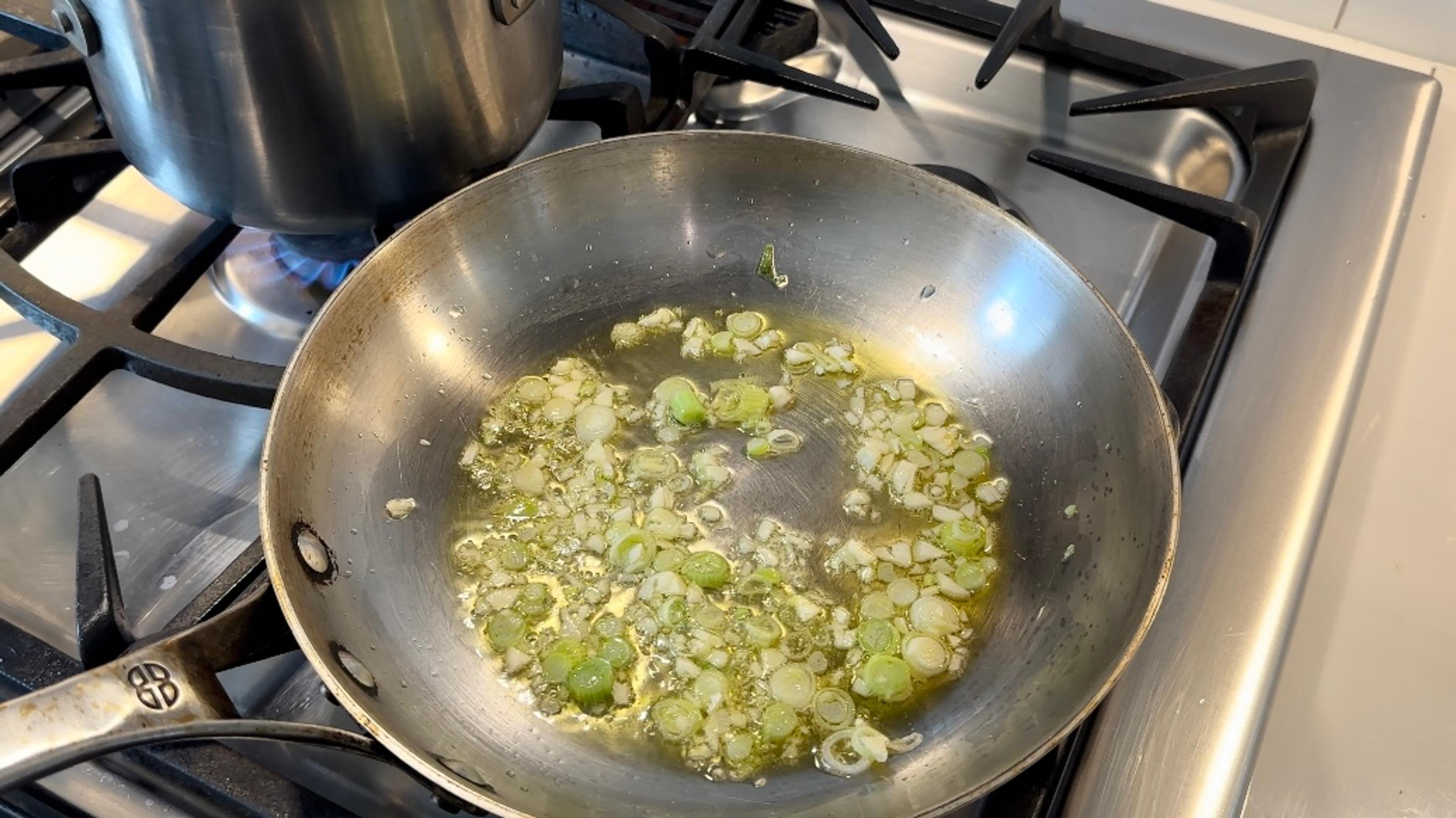 In a large pan, heat 3 tablespoons of garlic oil over medium-low heat, reserving the remaining oil for the broccolini. Add garlic and green onion whites, reserving the greens for garnish. Allow to sizzle until fragrant and golden.