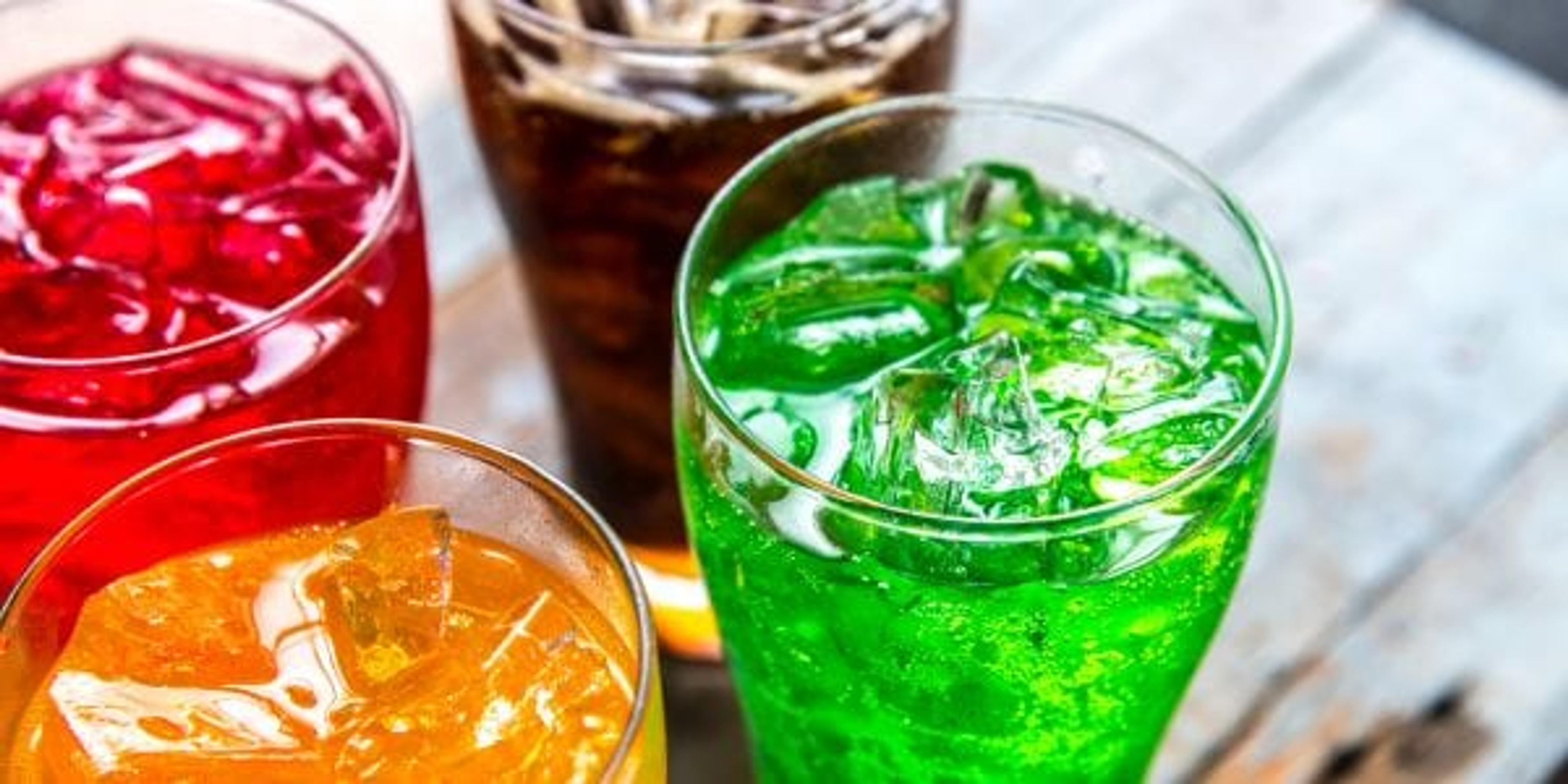 Red, orange, brown, and green drinks on a wooden surface